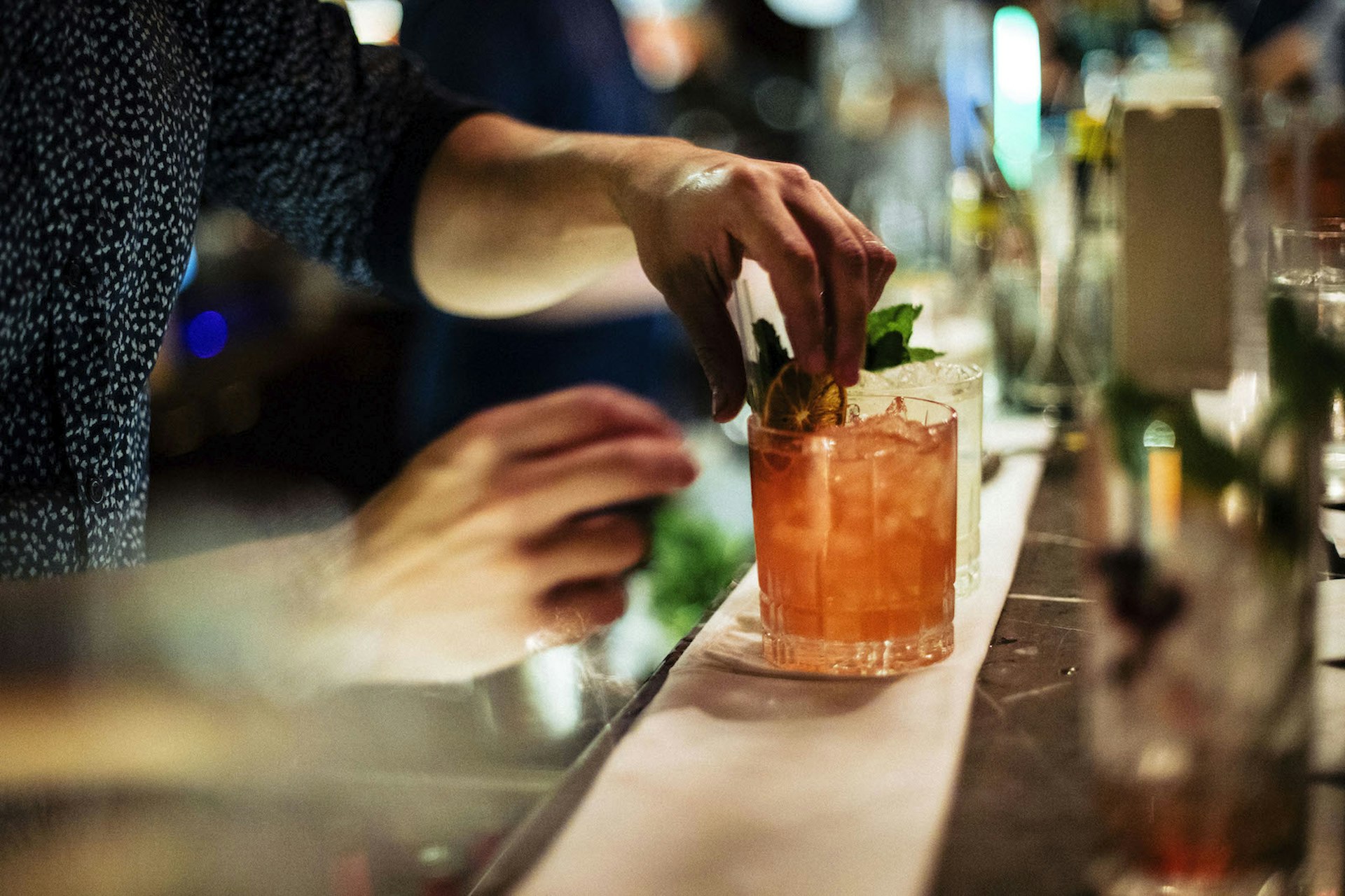 A woman's hands squeezing the lemon wedge into her cocktail