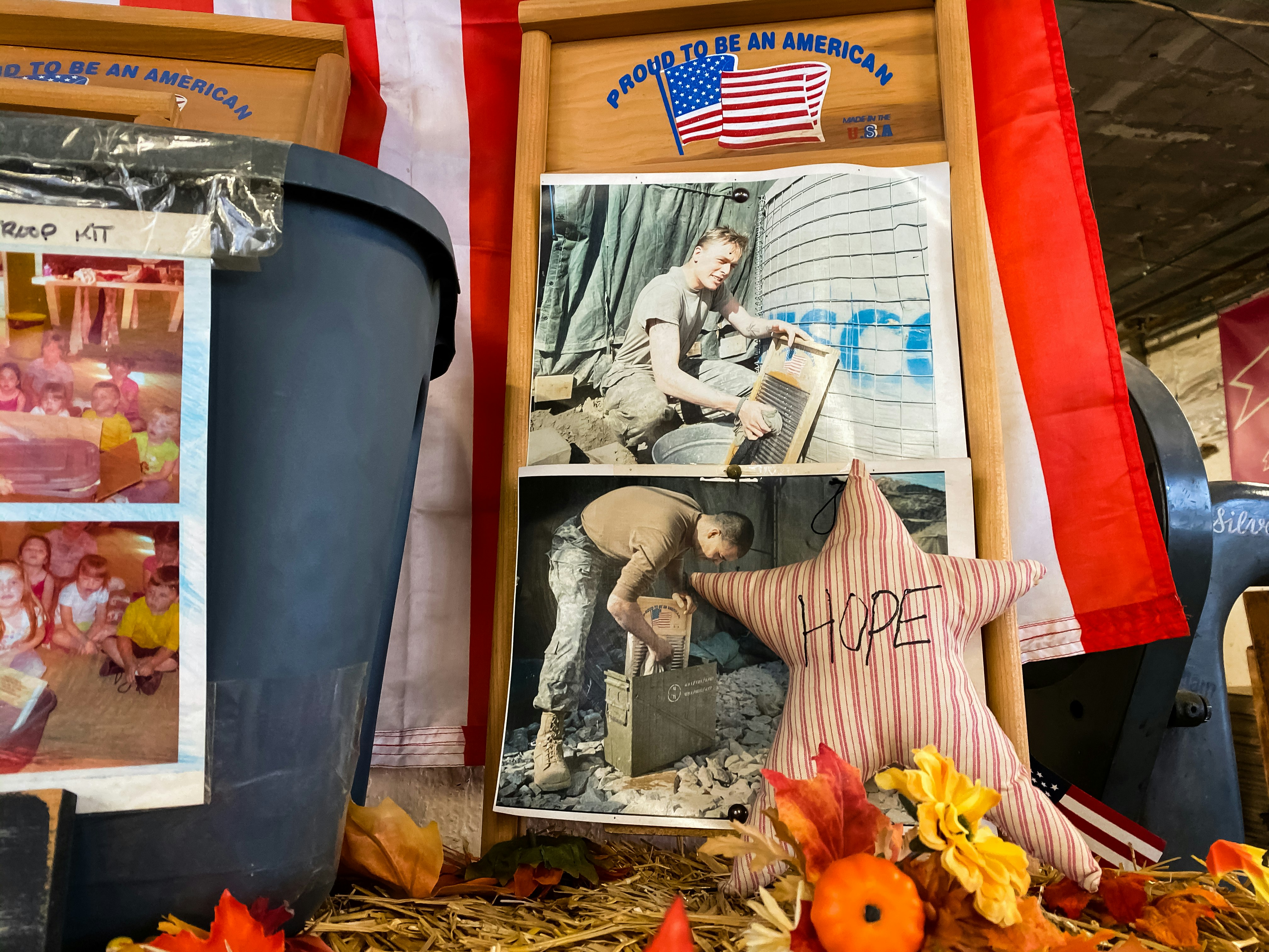 A photo of a photo of an active military officer using a washboard in the field along with a star pillow that reads hope surrounded by fall-inspired decor