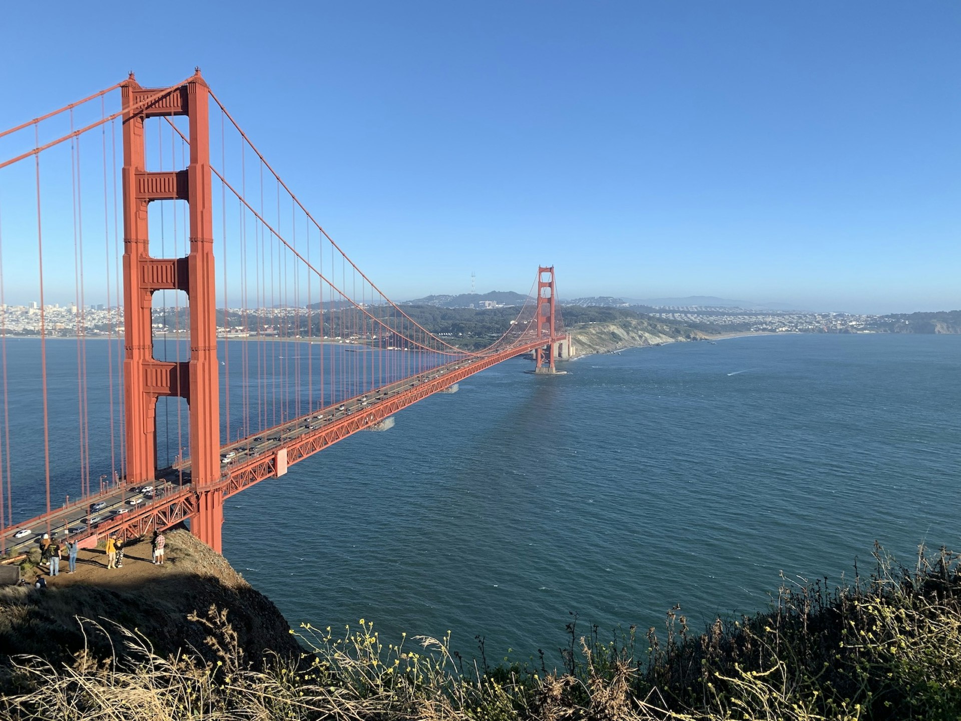 View of the Golden Gate Bridge, a small crowd of people visible at ground level
