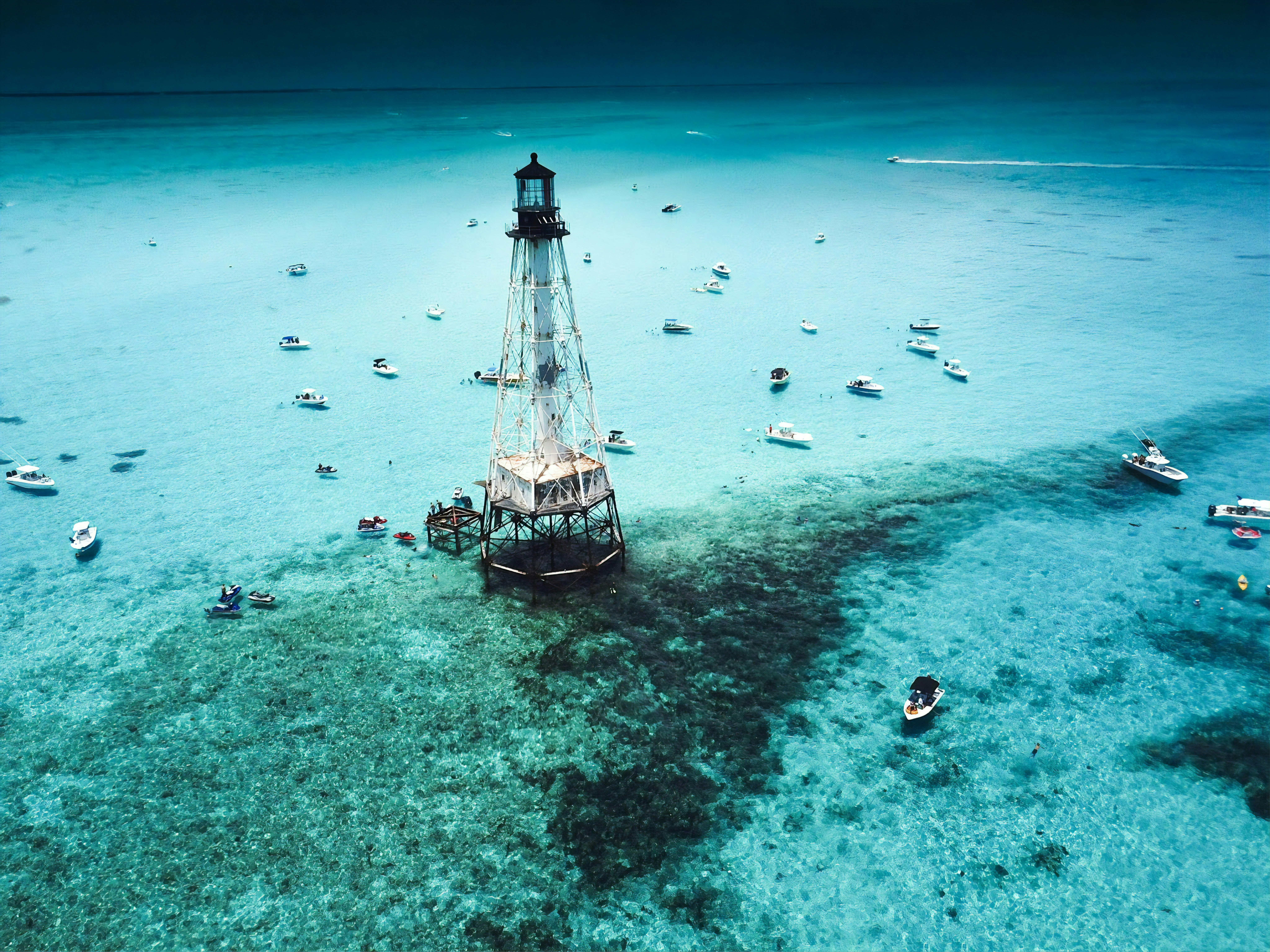 An aerial view of crystal blue waters, speckled by small fishing boats, with a rusty lighthouse in the centerview of Alligator Reef © Caitlyn Mentel.jpg