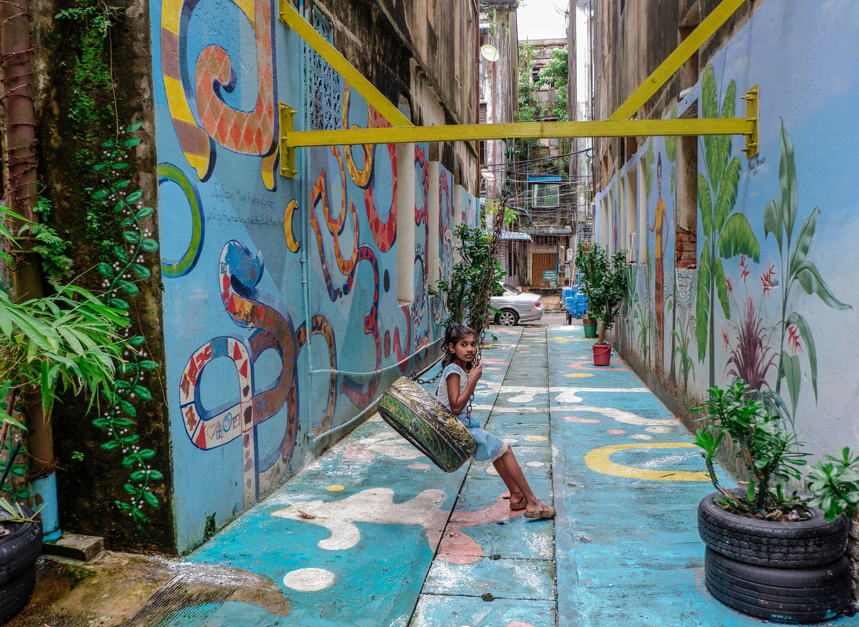 Girl plays on a swing in one of the cleaned up alleyways