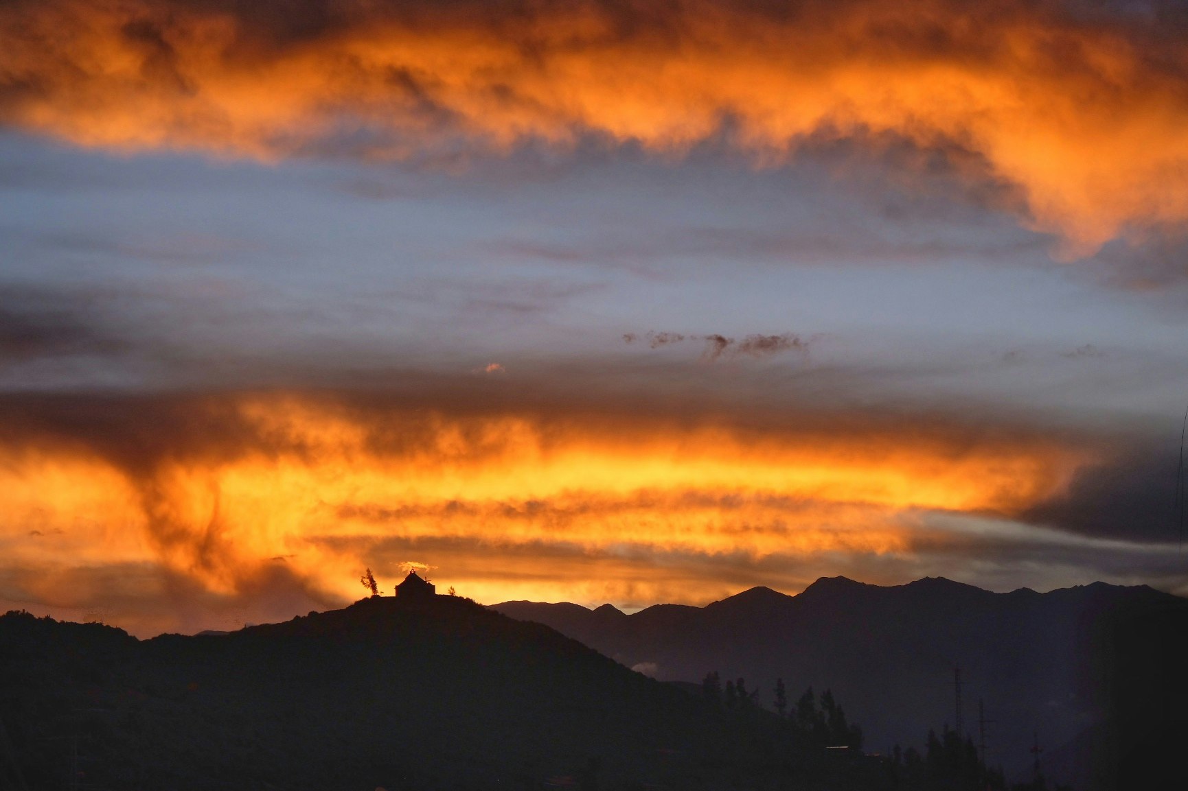 A sunset over Cabanaconde's hilltop church, which lights up the sky in bright orange and pink hues.