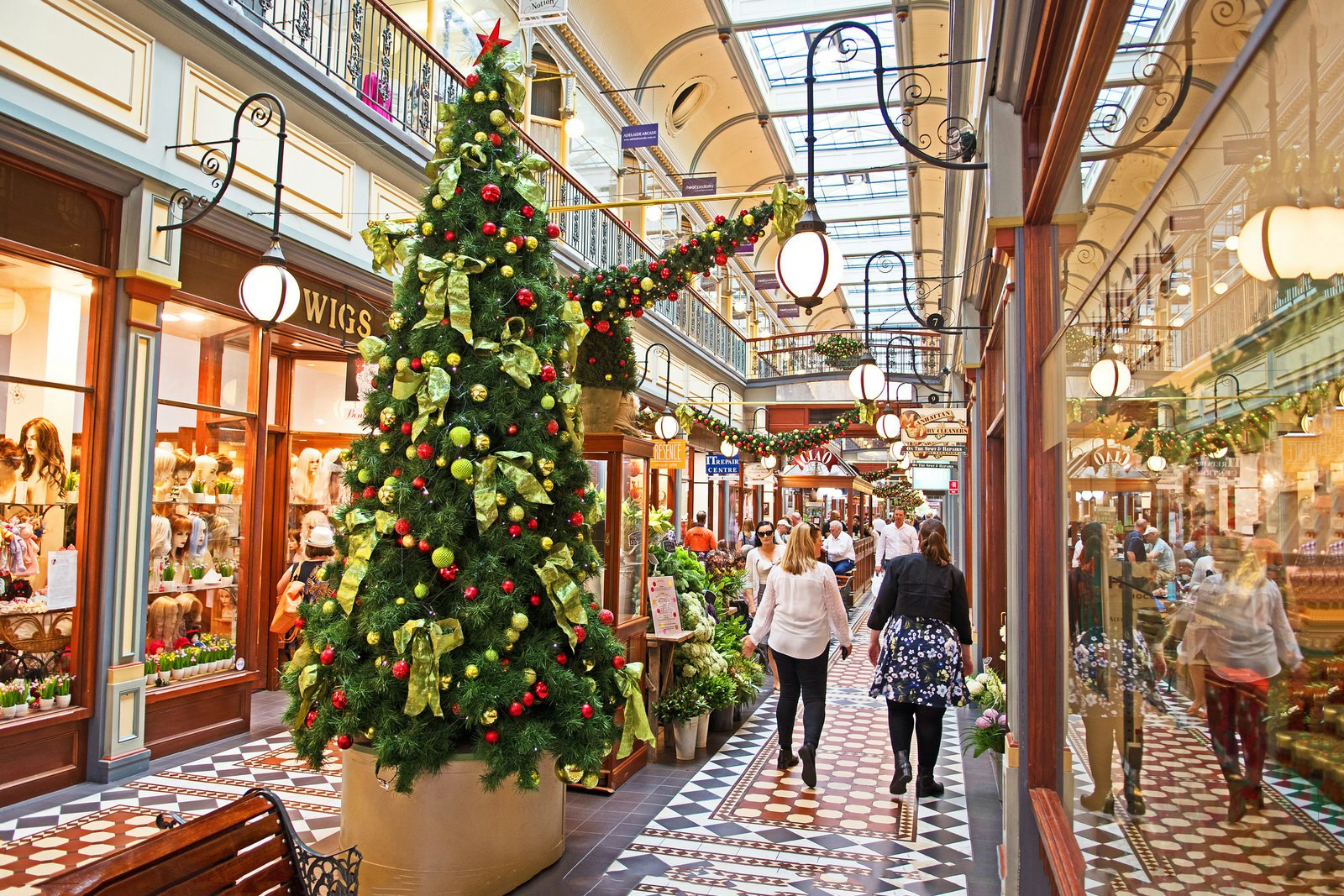 Shoppers stroll past Christmas decorations in the Adelaide Arcade, an old-fashioned, covered arcade with black-and-white tiled floor