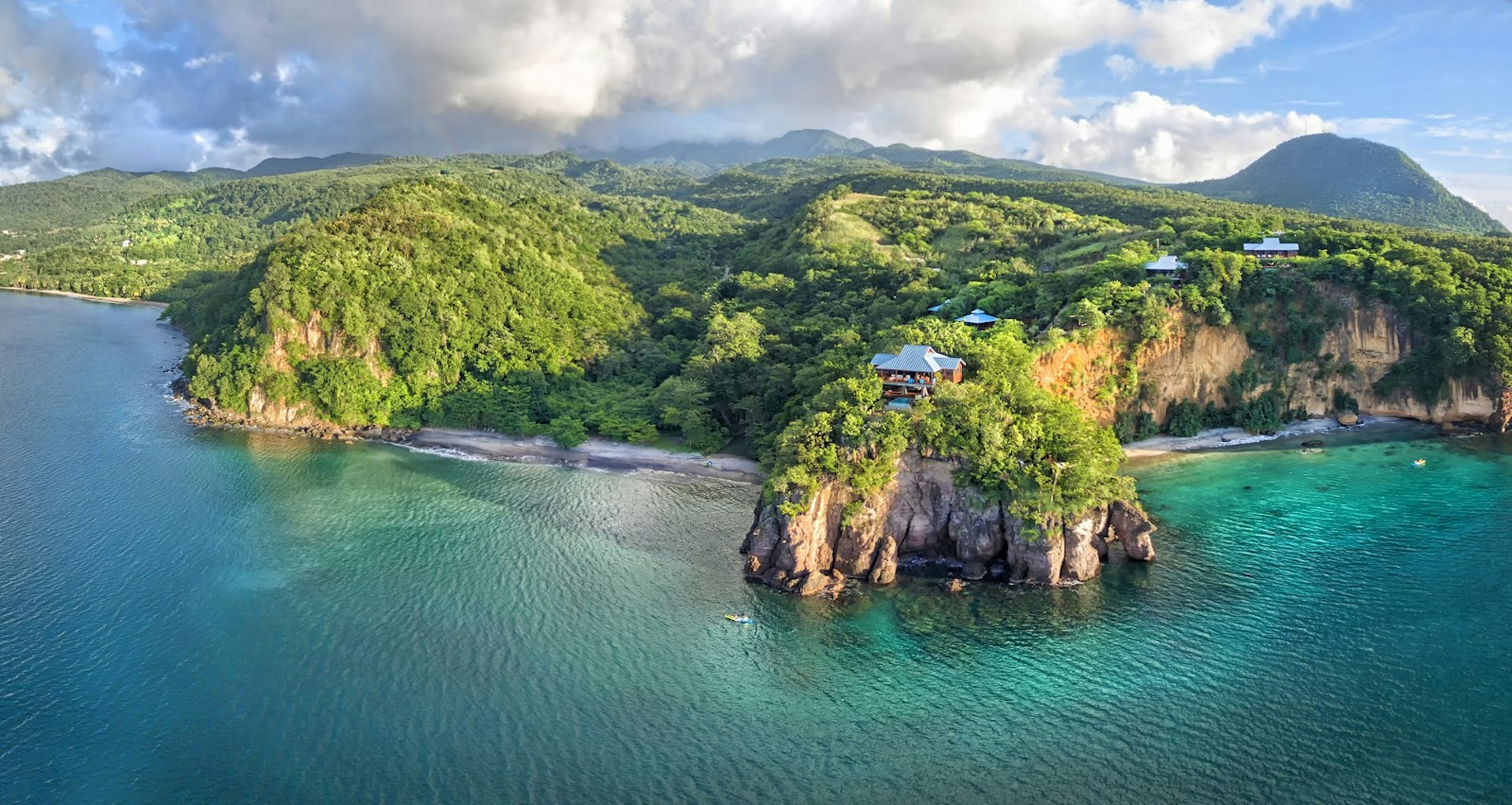 Aerial view of the Secret Bay Hotel which is built on a large cliff and surrounded by large trees; eco luxury resort