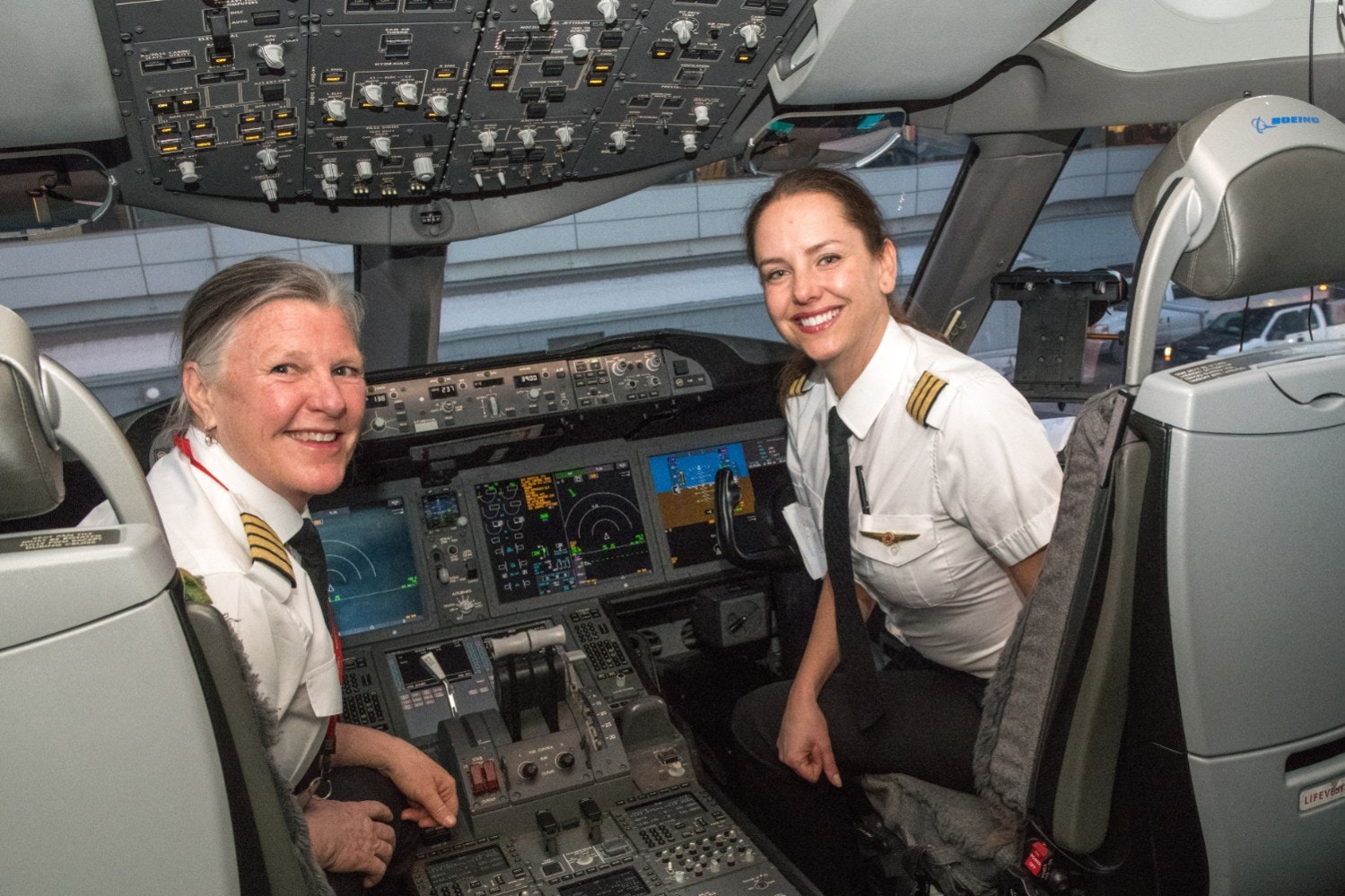 Two smiling female Air Canada pilots in the cockpit of a plane