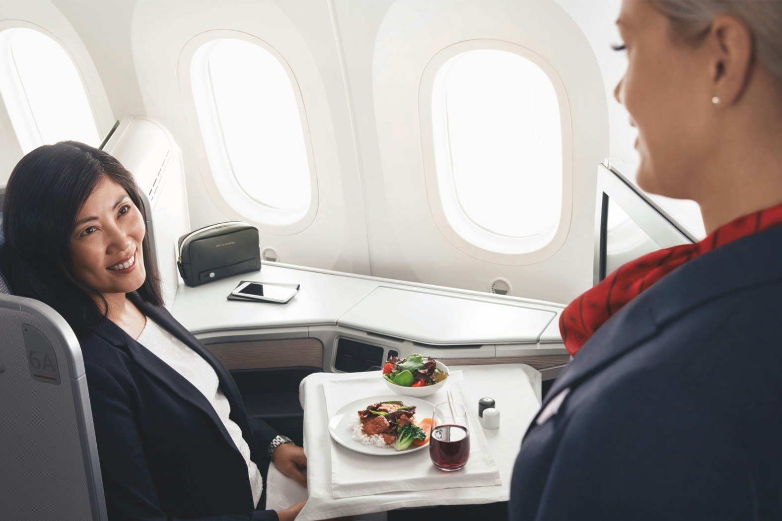 An Air Canada hostess serving a meal to a female passenger