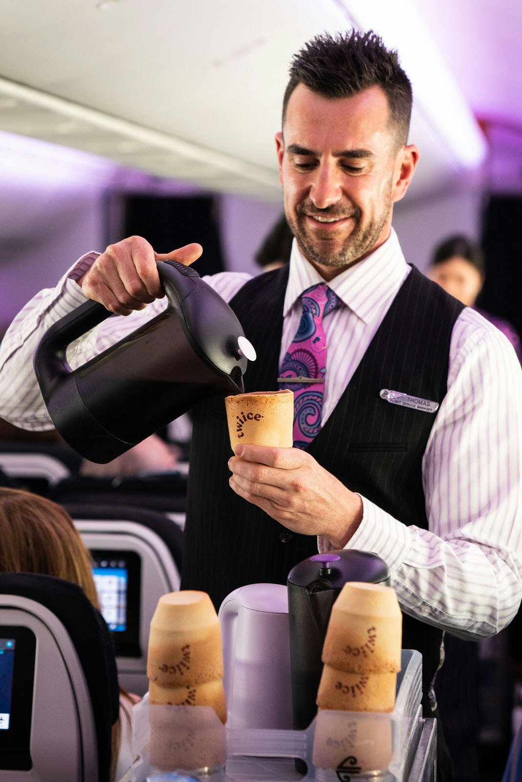 An Air New Zealand air steward pouring coffee into an edible biscuit cup on board.