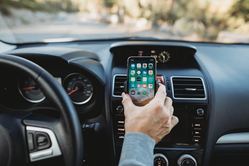 en hand som håller en telefon på Kenus Airframe Wireless vent mount, framför en bils instrumentbräda