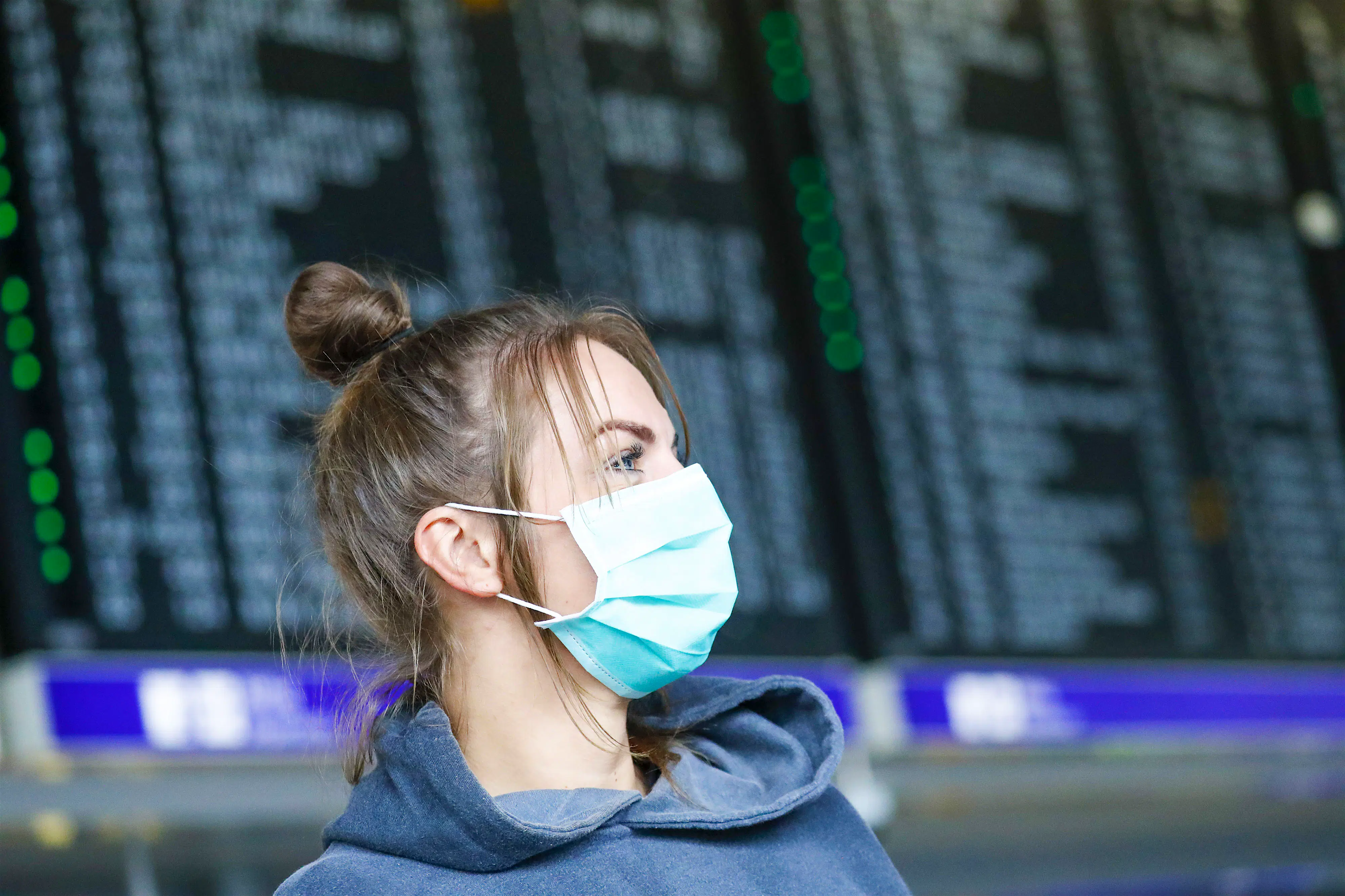 Airlines coronavirus.jpg Female passenger wearing a face mask in front of an airport departures screen