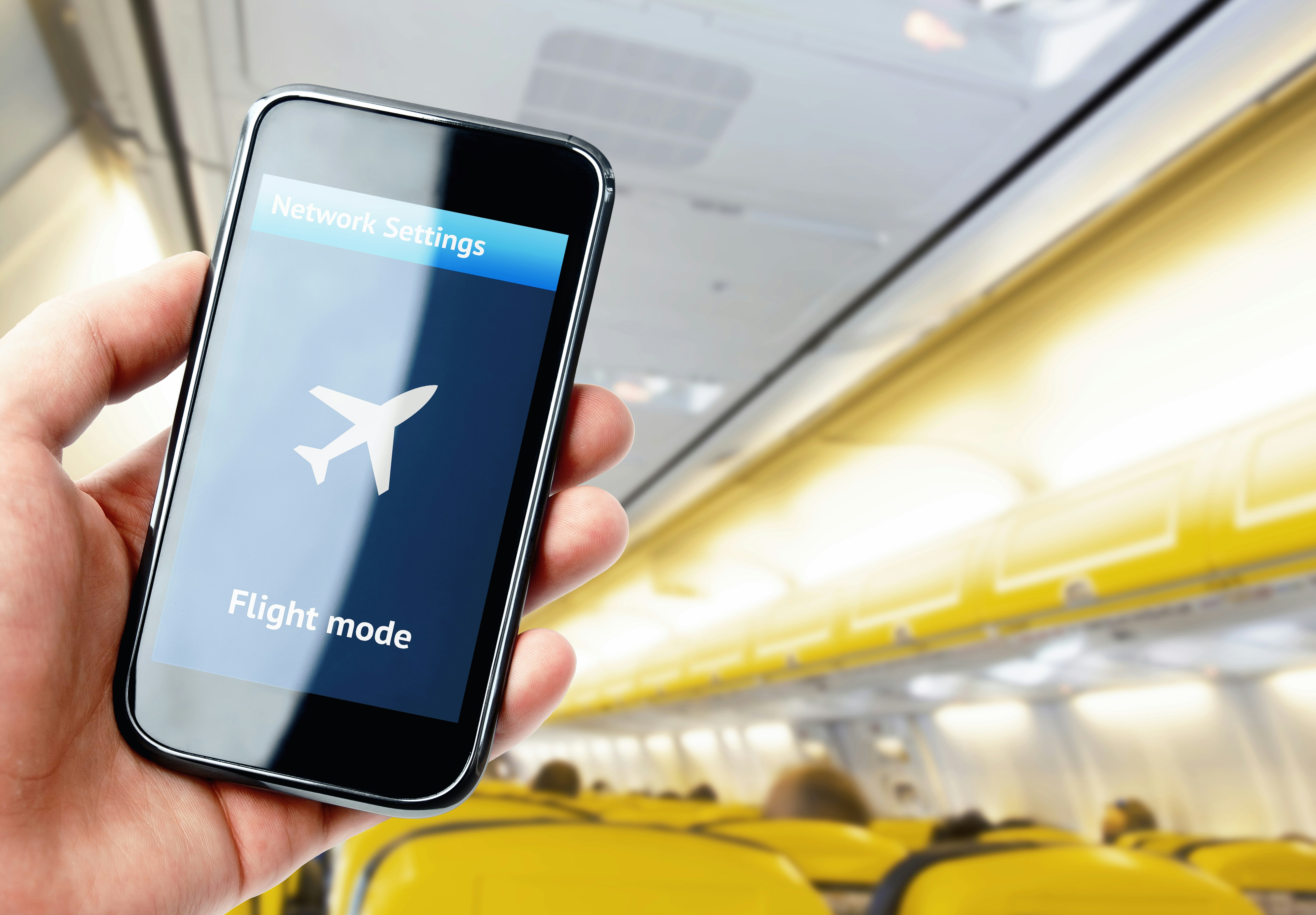 Hand holding smartphone inside the plane with flight mode activated