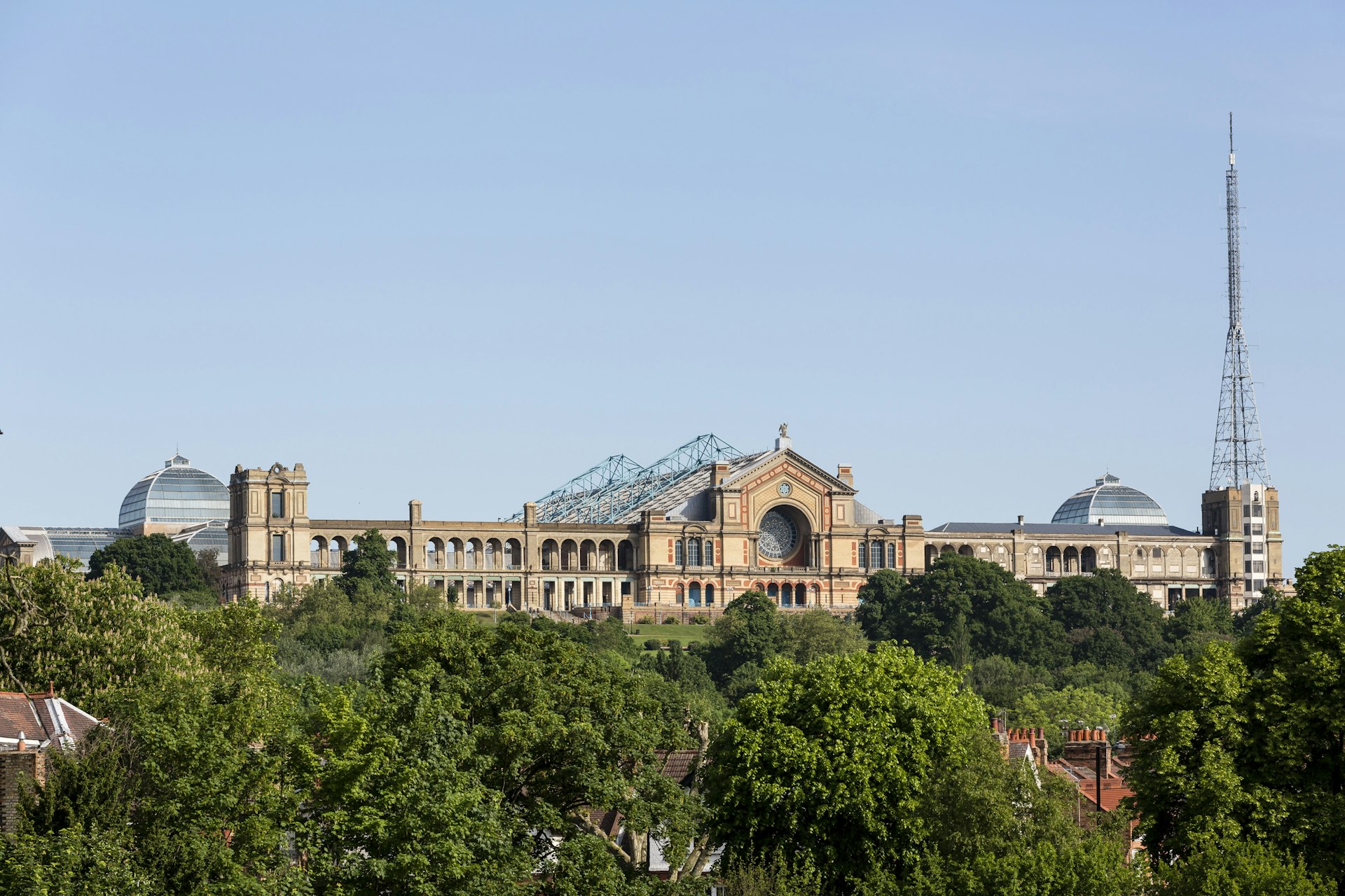 Alexandra Palace positioned on a hilltop in London, with green trees in the foreground.