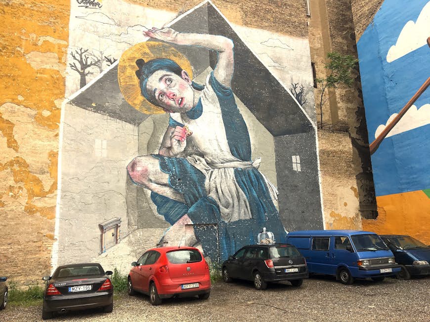 A mural of a young girl filling the space of a house whilst eating a cookie. She reaches above her head as it touches the ceiling of the house.