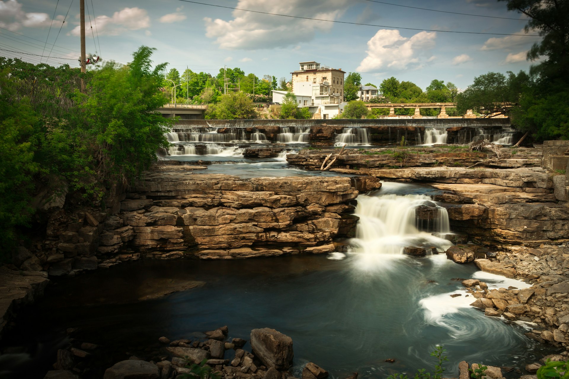 Many small waterfalls cascade over rocks in into a small pool in the heart of Almonte, Ontario Canada.