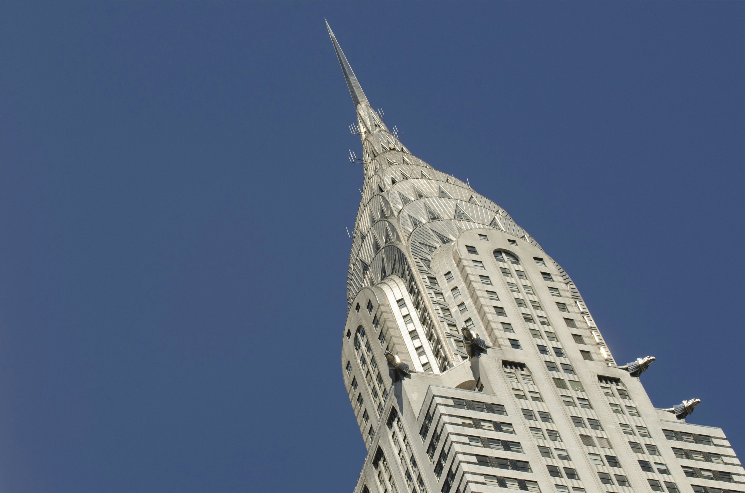 The silver-gray top of the Chrysler Building is framed at an angle against a blue sky; Best American architecture