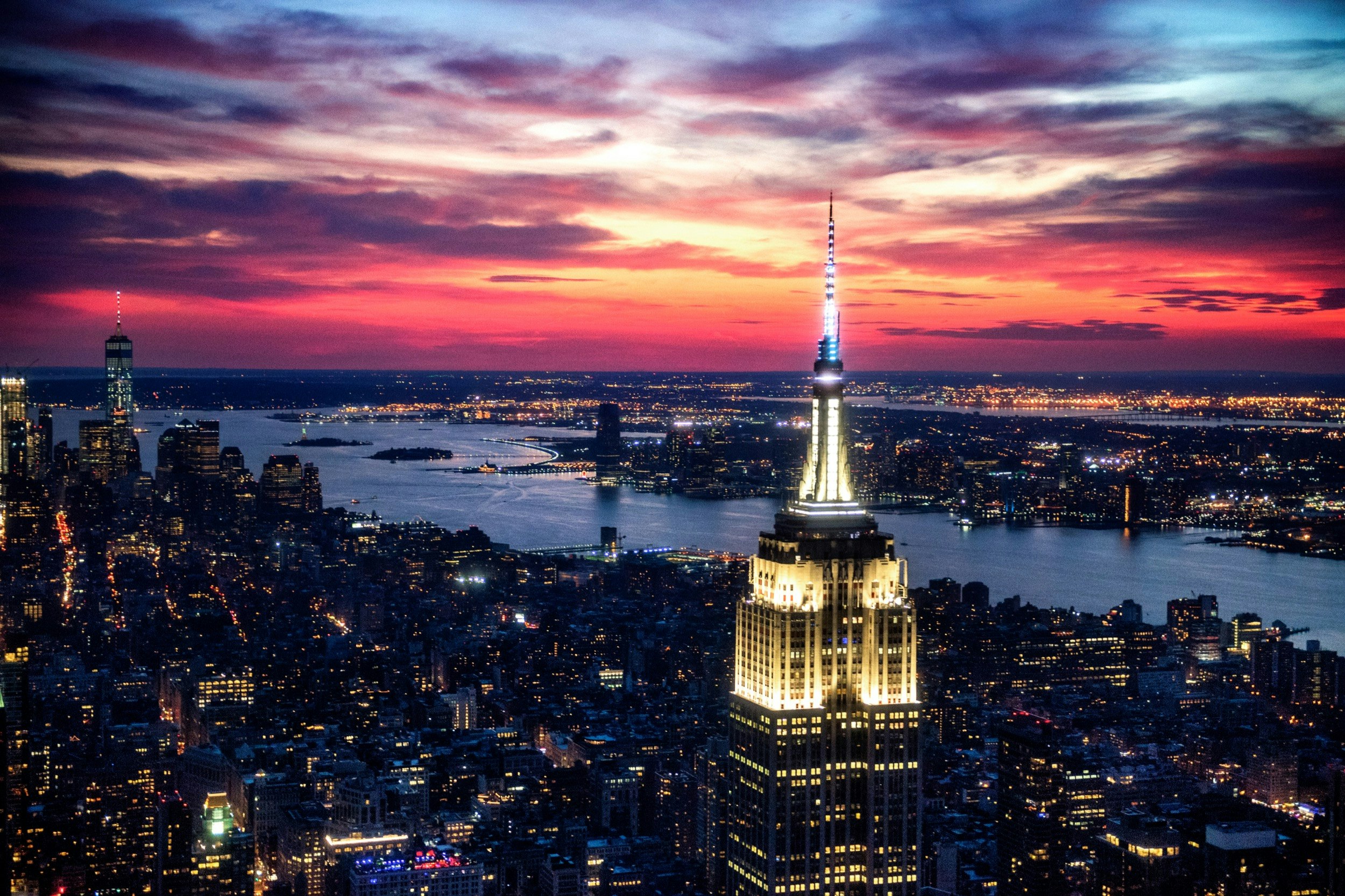 The top of the Empire State Building in New York City is illuminated at late dusk as the lights of the city are spread out below; Best American architecture