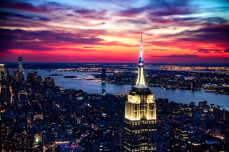 The top of the Empire State Building in New York City is illuminated at late dusk as the lights of the city are spread out below; Best American architecture