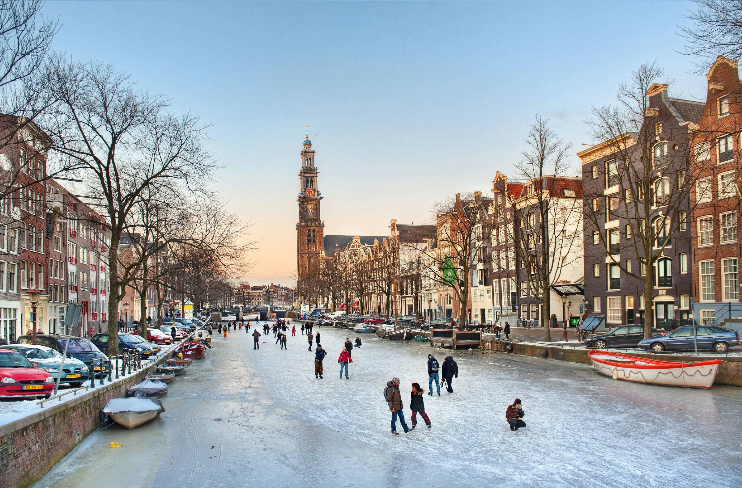 Skaters on the ice in Amsterdam’s Prinsengracht canal on a winter evening.