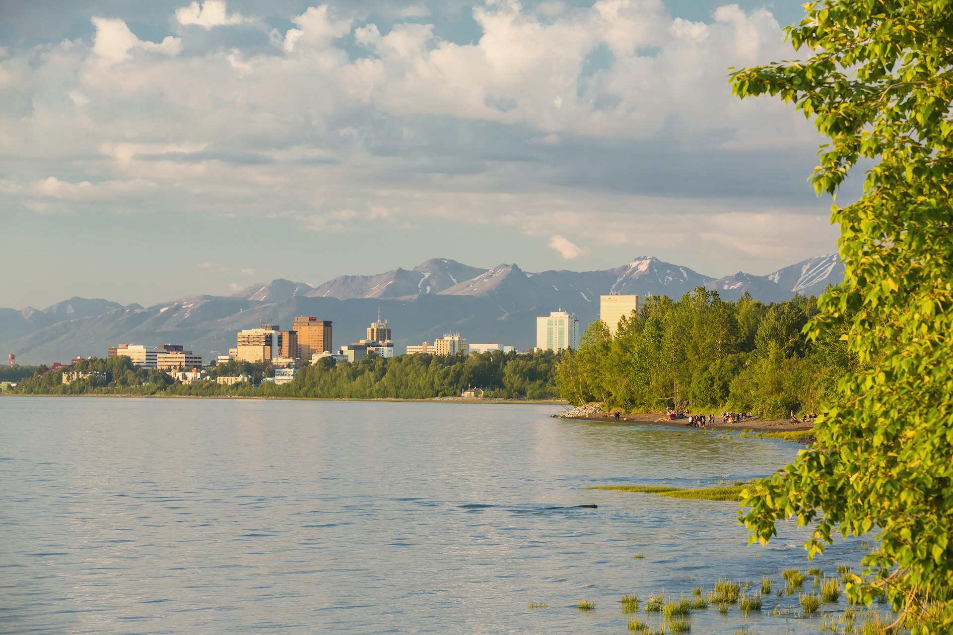 Anchorage city skyline seen from the Tony Knowles Coastal Trail during high tide with mountains in the background