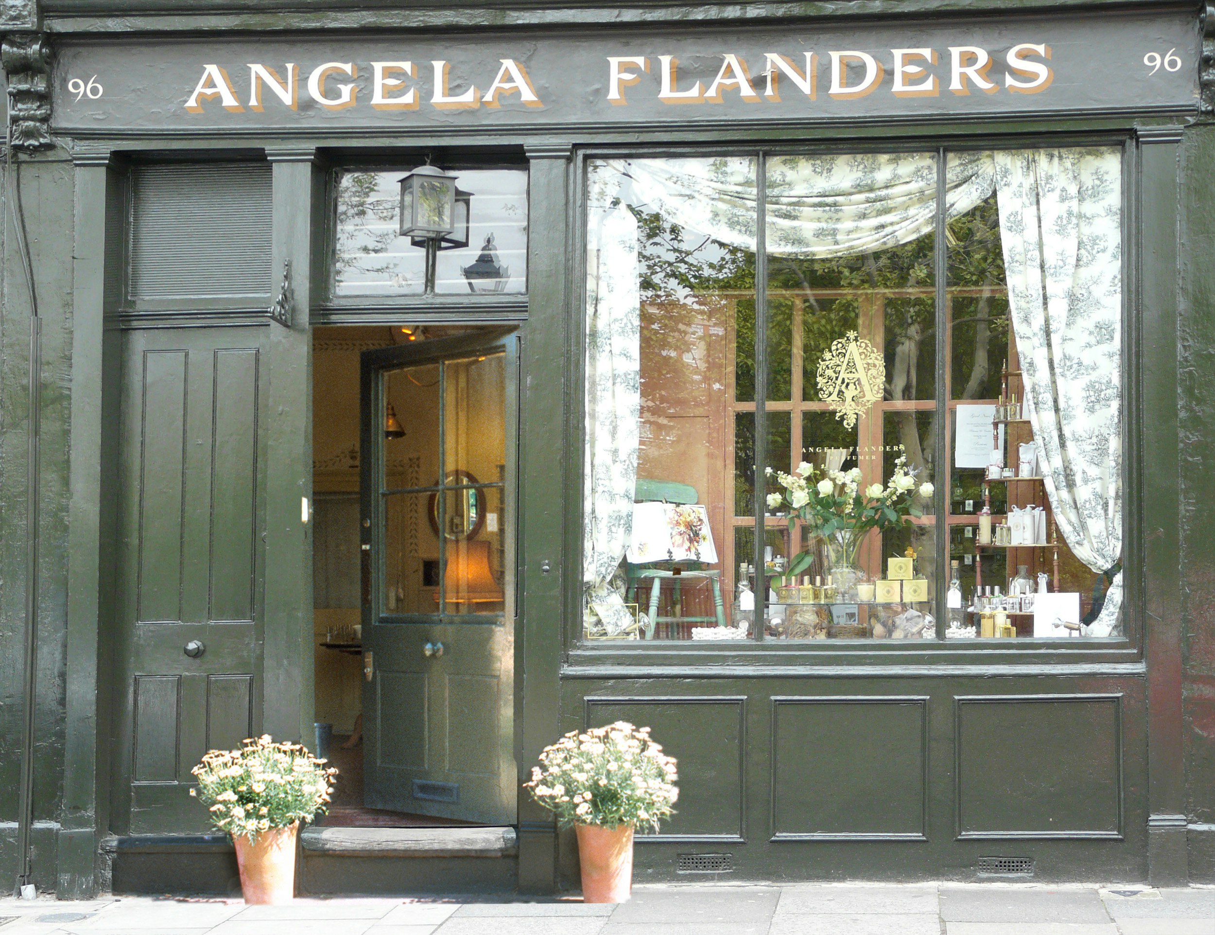 The green Angela Flanders storefront in east London, with curtained windows displaying flowers and perfume inside.