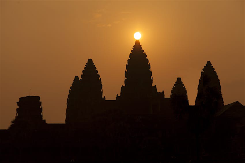 The sun rises directly behind a stone temple at Angkor Wat during the spring equinox. 