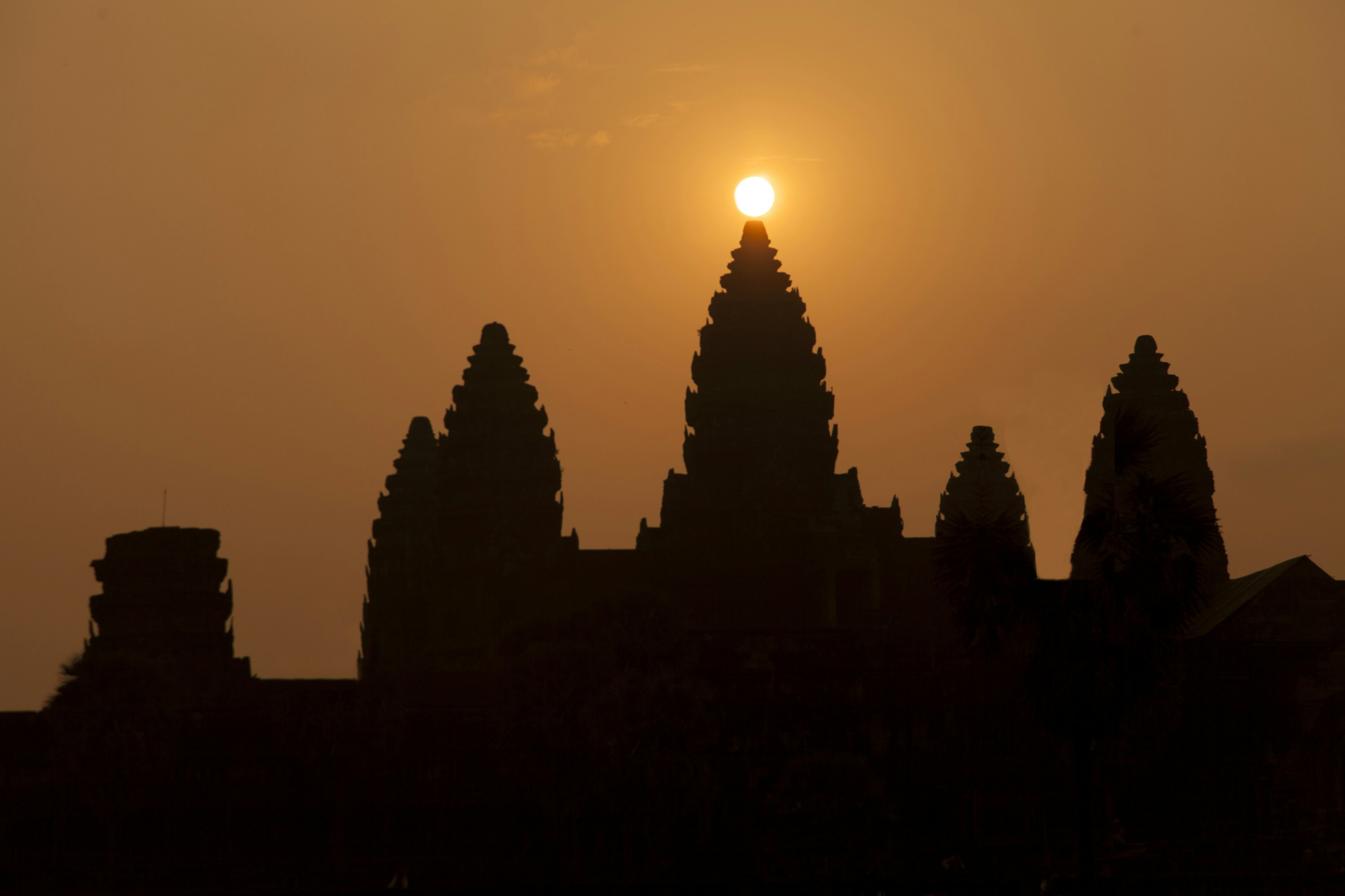 The sun rises directly behind a stone temple at Angkor Wat during the spring equinox. 