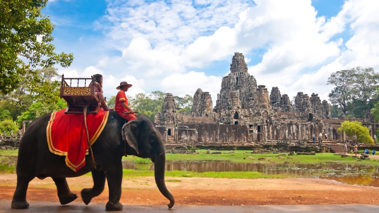 Visitor riding an elephant in front of Angkor Wat