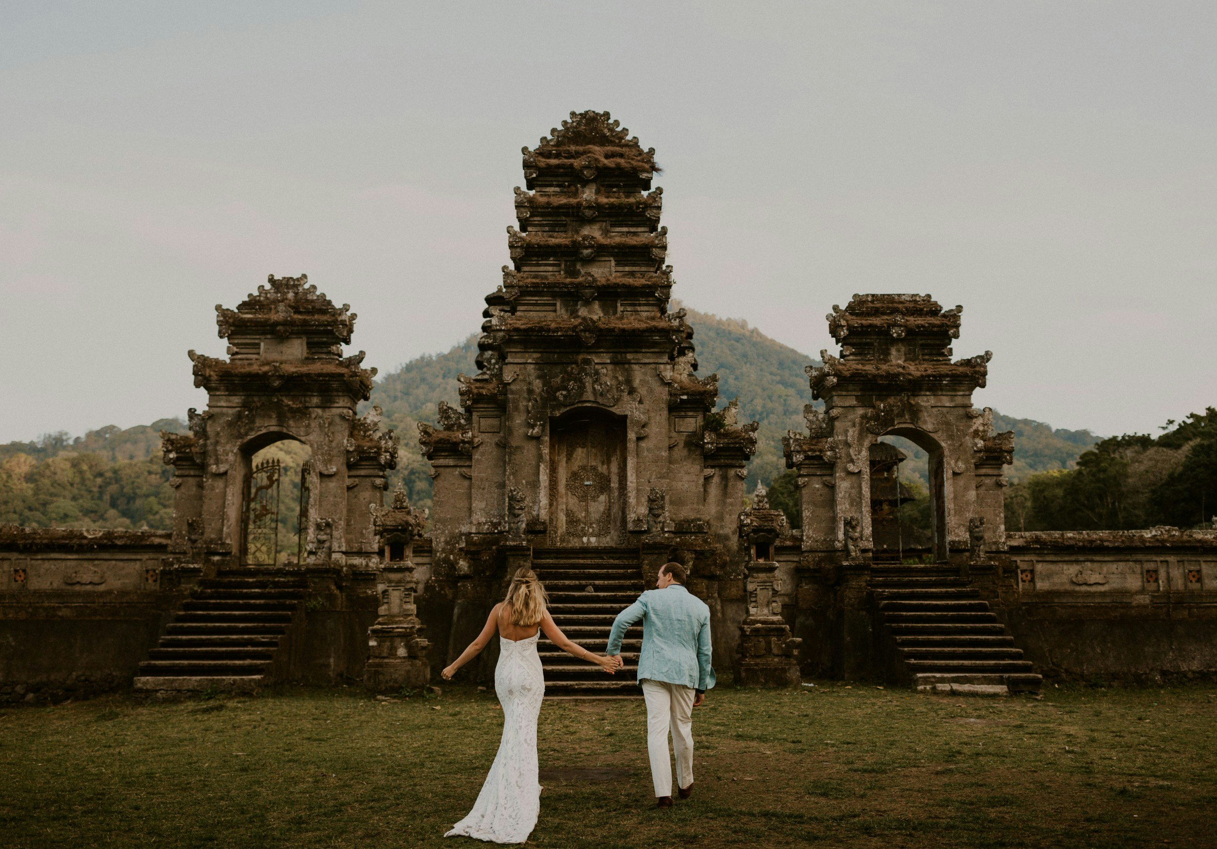 A bride and groom in front of a temple in Bali.
