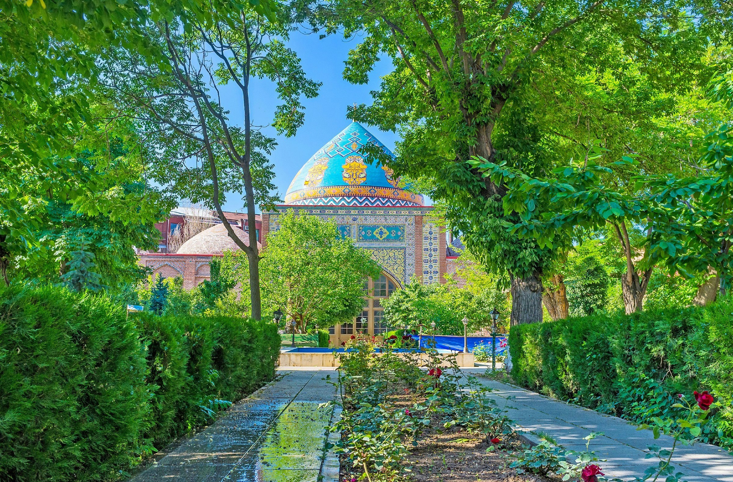 The shady alley of a garden that leads to the Shia Blue Mosque, decorated by colorful tiles, Yerevan, Armenia
