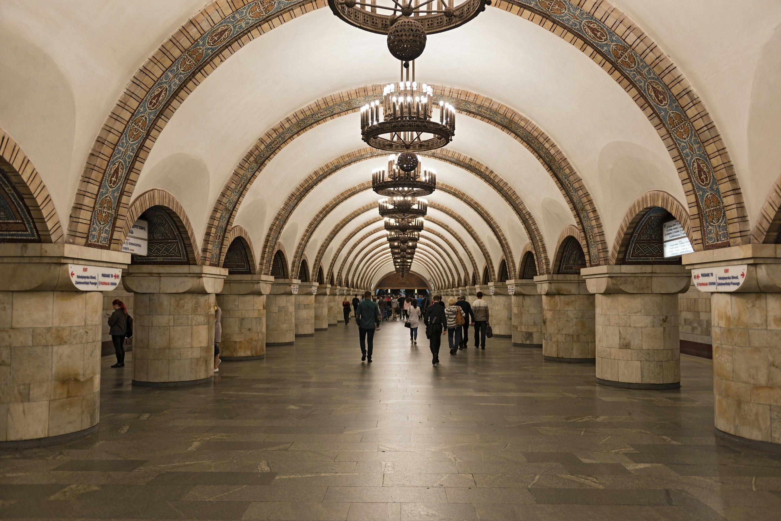A long wide corridor with a vaulted ceiling and ornate chandeliers hanging down in Aresnalna, Kiev