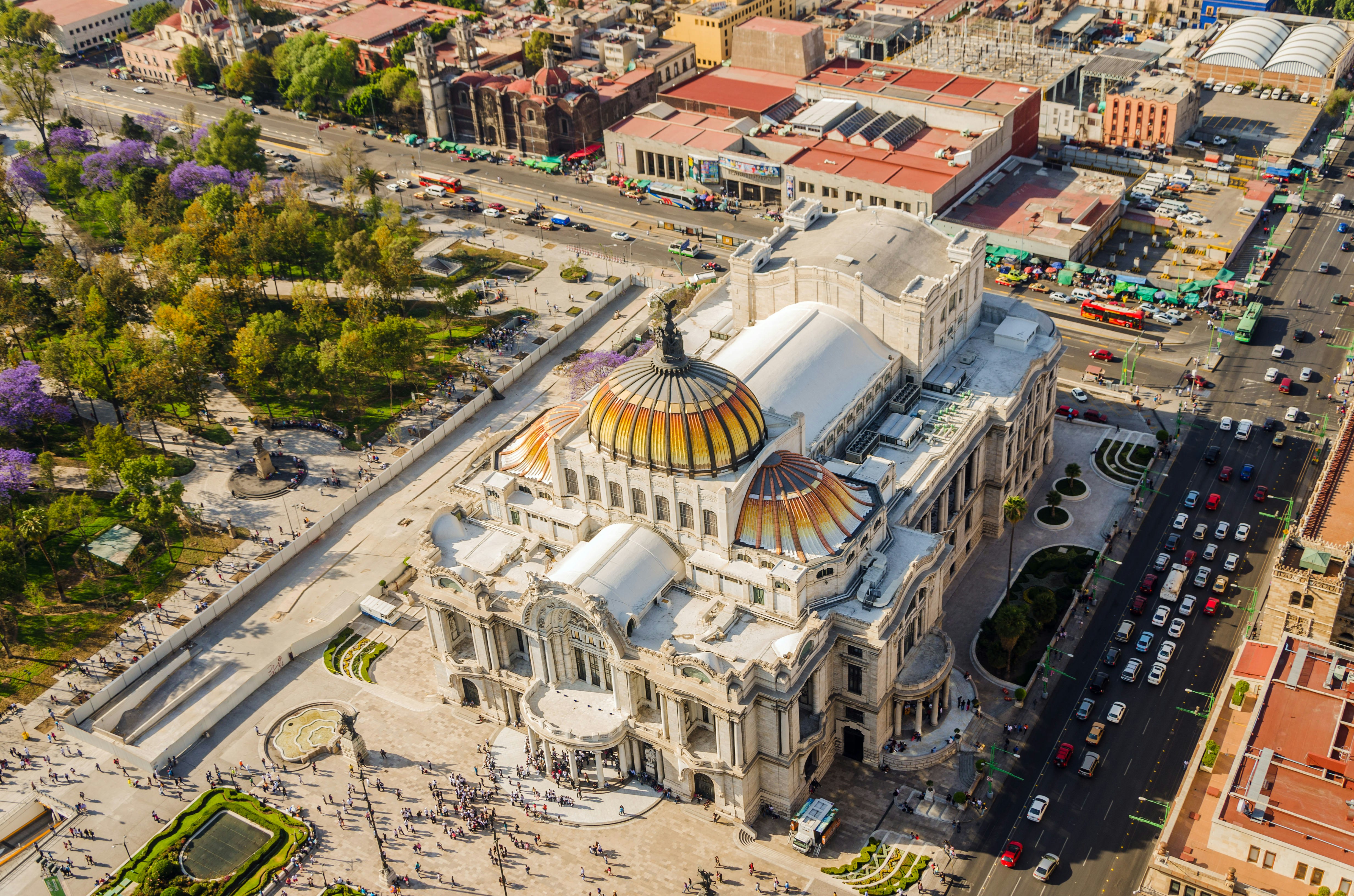 An aerial view of Mexico City's Fine Arts Museum, a grand building with a domed ceiling, which is surrounded by busy streets.