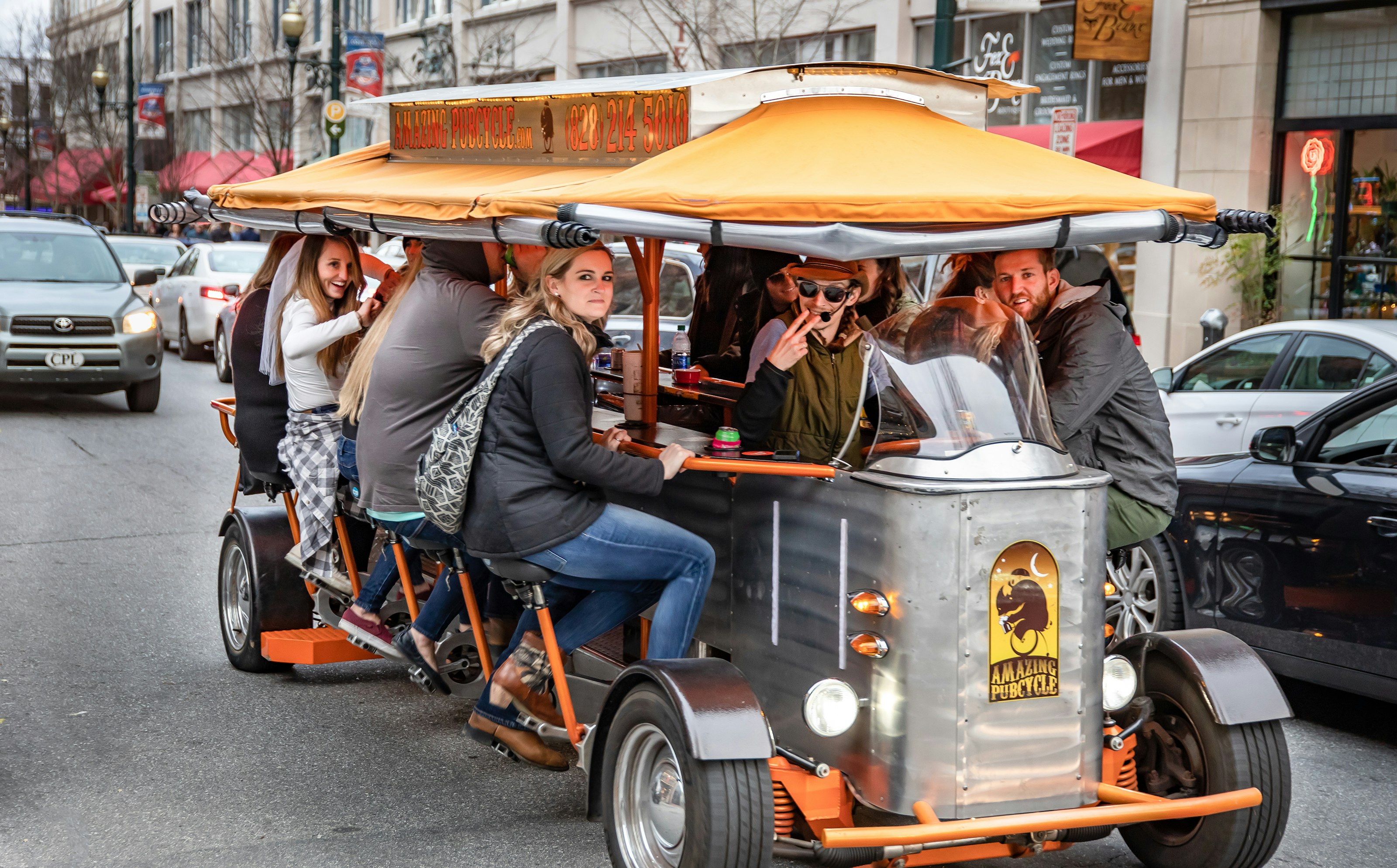 A group of people move through downtown Asheville in a pedal tavern; bachelorette party
