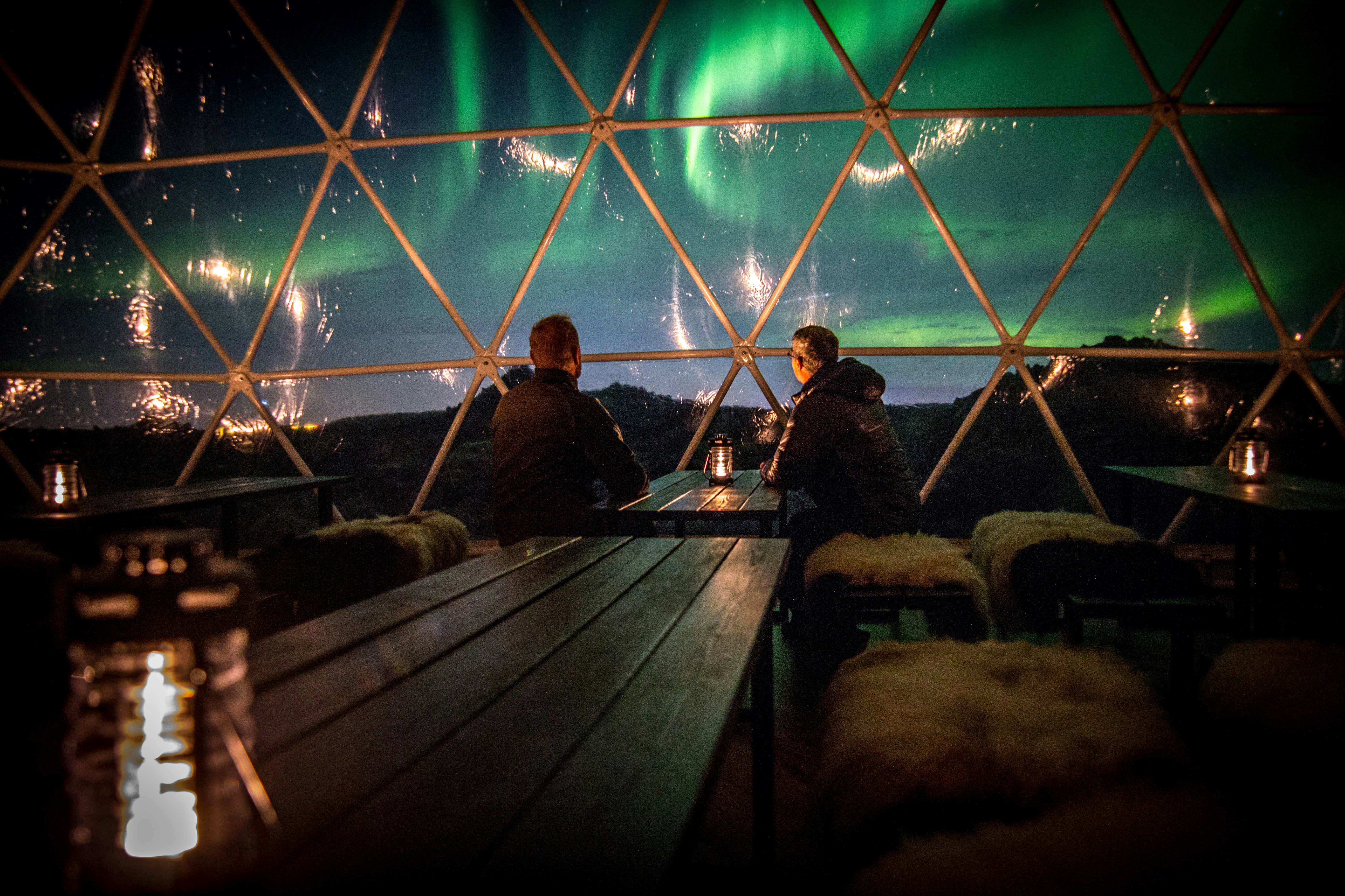 People view the Northern Lights from the cosy confines of a cabin