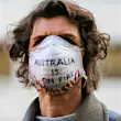 A woman wearing a white air pollution mask with 'Australia is on fire' written on it.