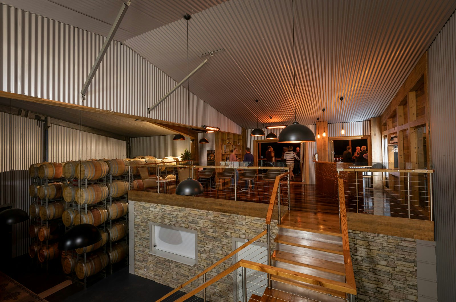 The warehouse-like interior of Aztes Corner Wines in Barossa Valley. Casks of wine are stacked on the left with a small bar on the right.
