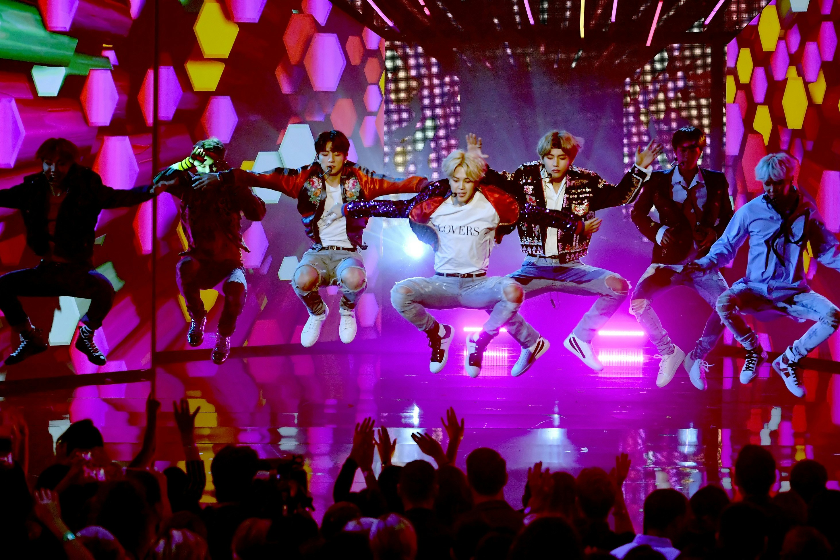 BTS leaping in the air while performing onstage during the 2017 American Music Awards