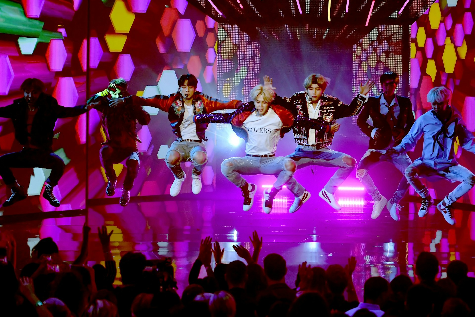 BTS leaping in the air while performing onstage during the 2017 American Music Awards