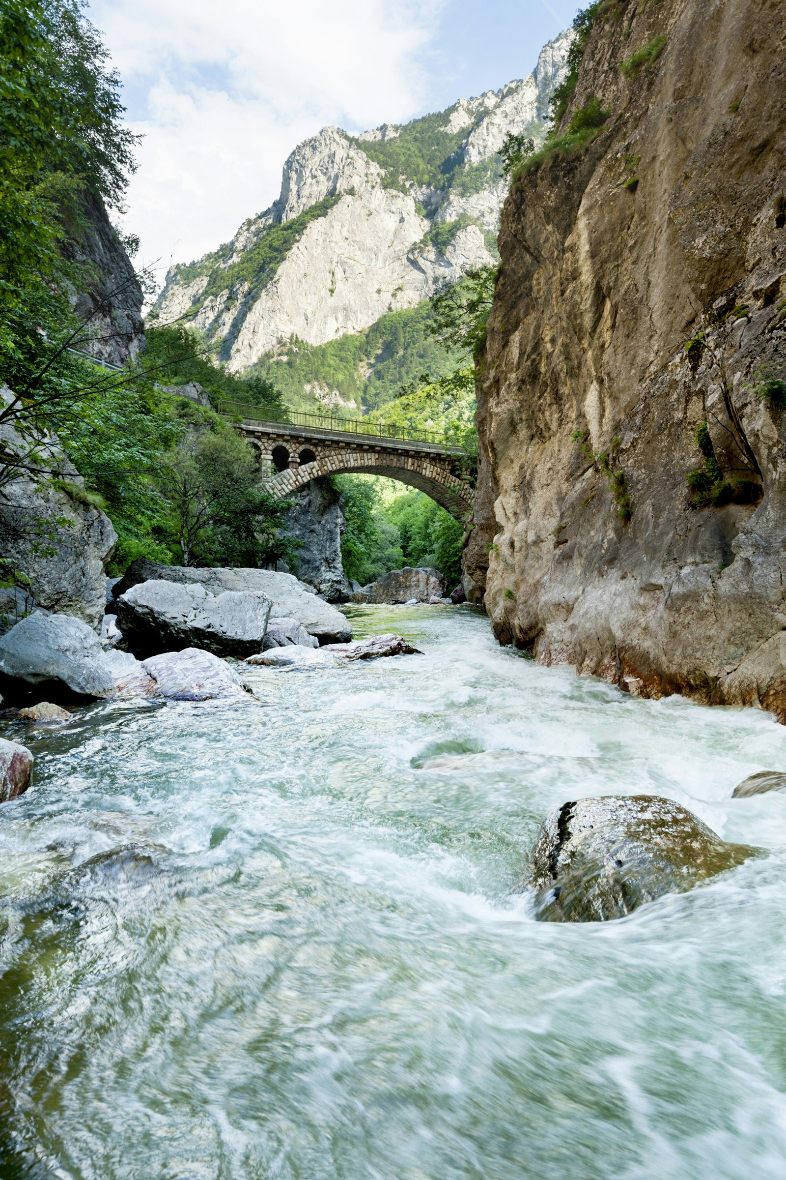 A stone bridge spans a churning river in Rugova Gorge
