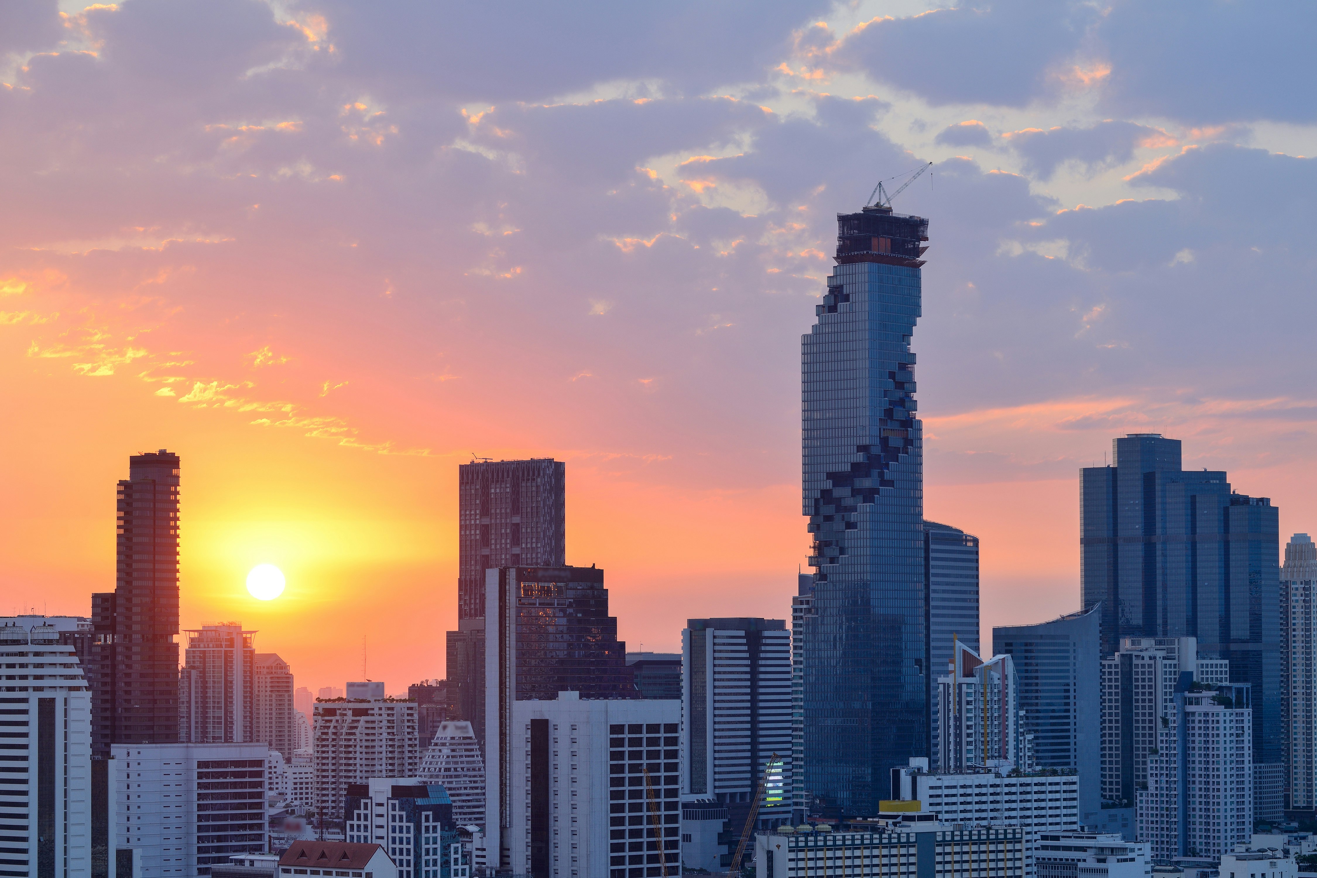 The skyline of Bangkok, Thailand, with the King Power MahaNakhon building in shot. The sun is setting. 