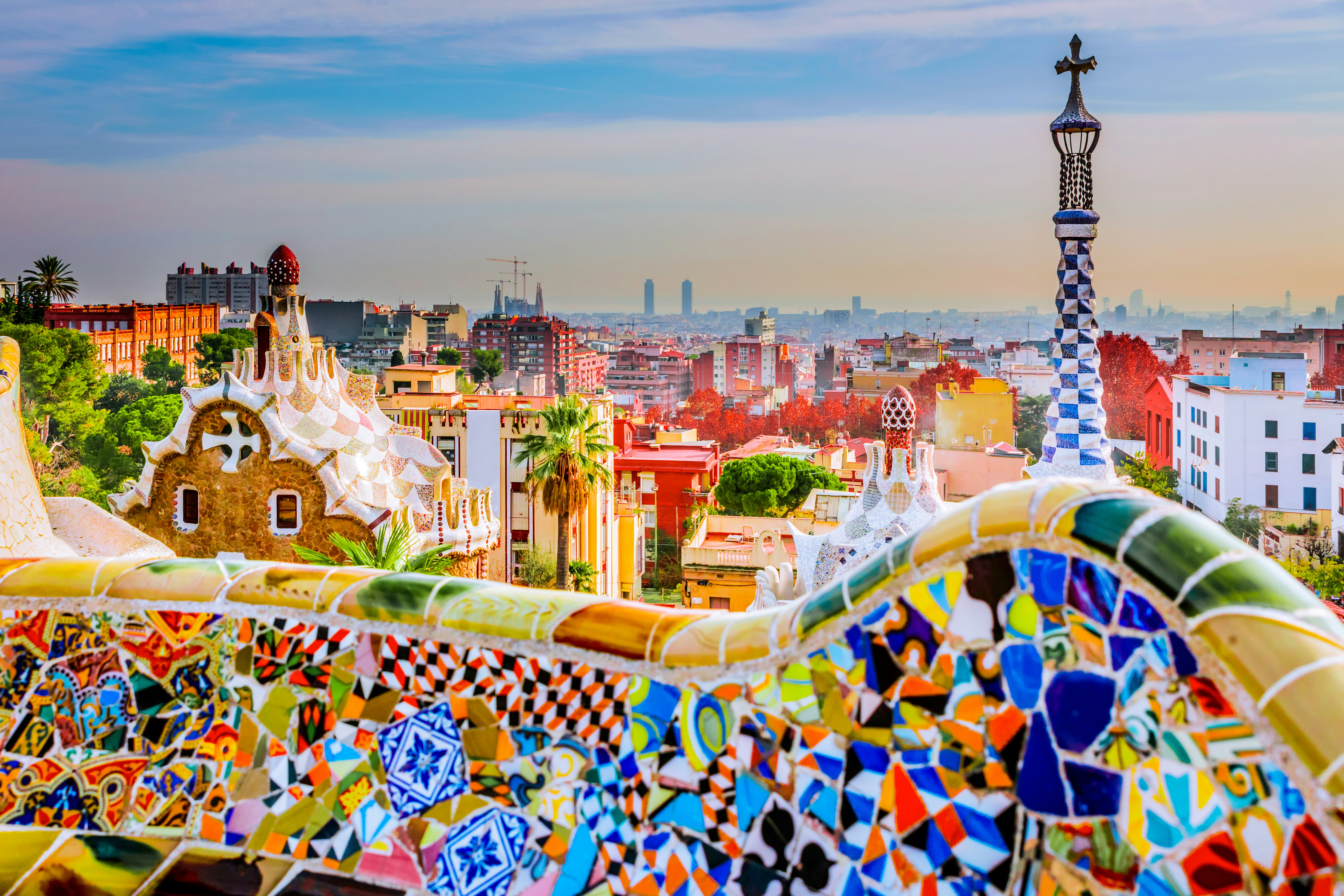 Colourful mosaics on the seats of Park Guell with the Barcelona skyline.