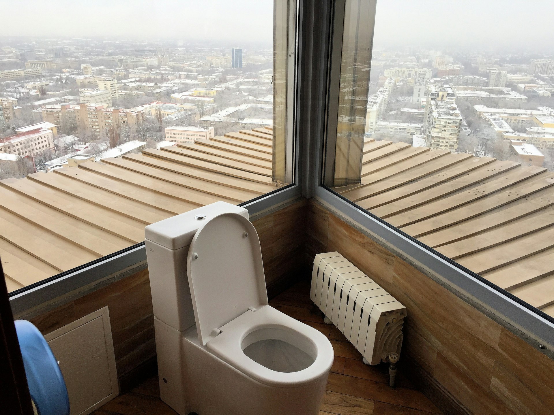 The bathroom of the Hotel Kazakhstan's top-floor restaurant. The toilet is surrounded by mid-length windows on all sides, with views looking out over the city.