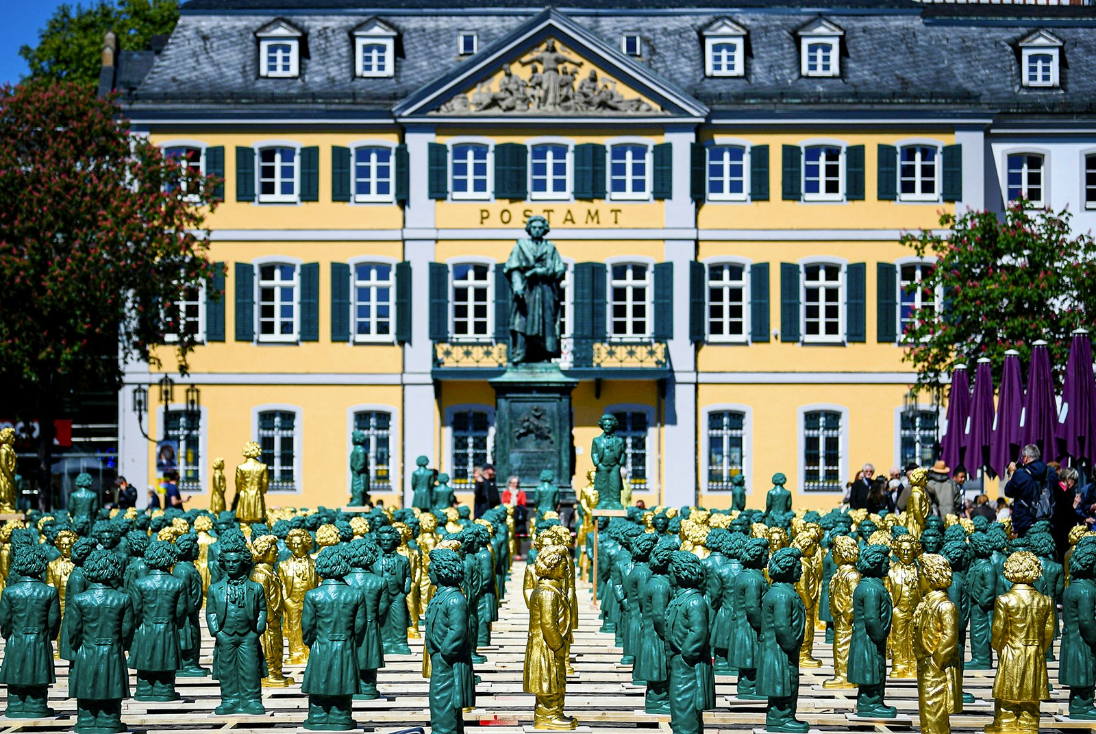 Green and gold sculptures representing Beethoven are lined up in Bonn's Münsterplatz.