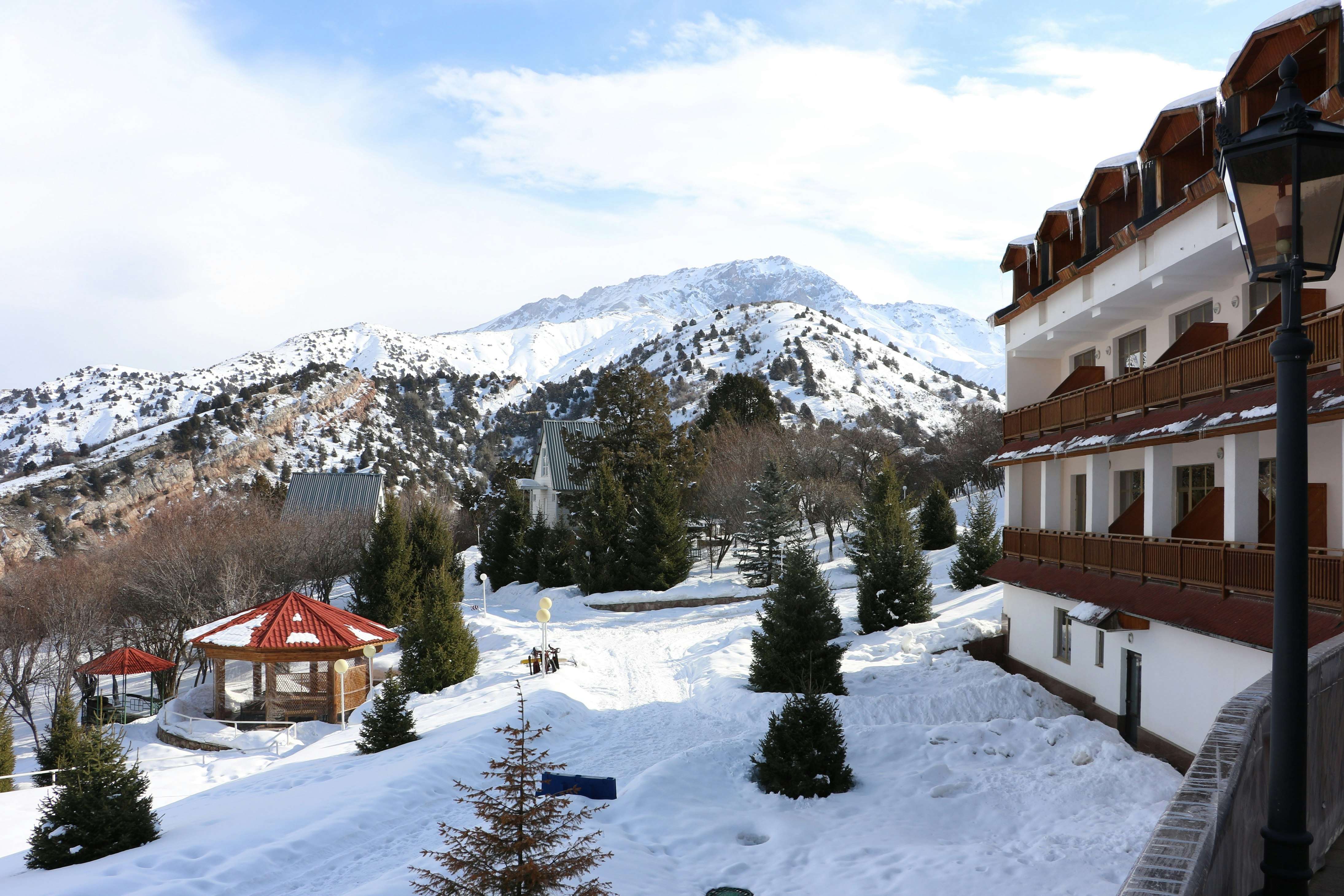 A view looking out over a snowy landscape, taken from the balcony of a hotel. Some of the hotel is visible in the shot, which has a traditional ski lodge look.