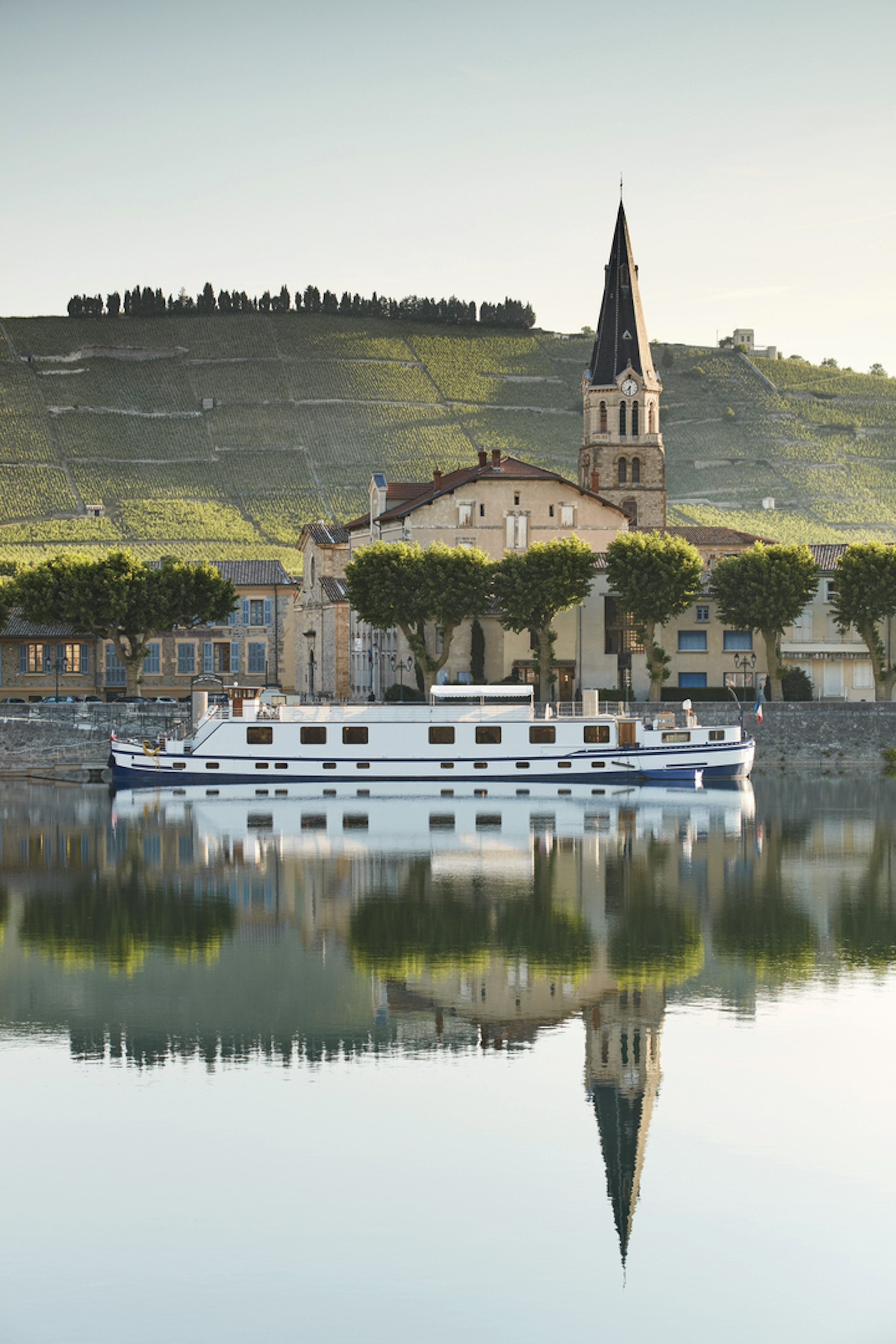 A small river cruise boat sails through a scenic French village