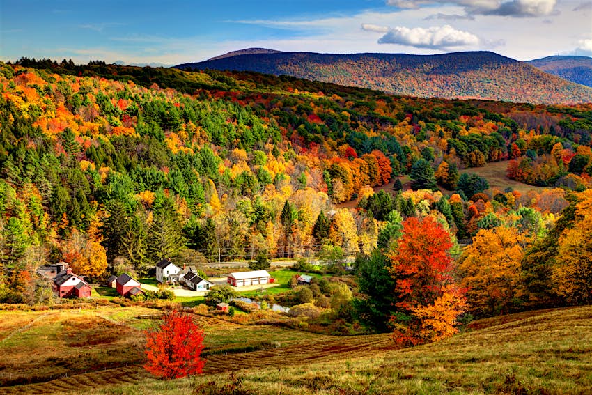 Fall colors fill a picturesque Massachusetts valley as a small village peeks through; New England fall foliage road trip