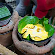Bibingka being prepared in terracotta pots over hot coals, wrapped in banana leaves