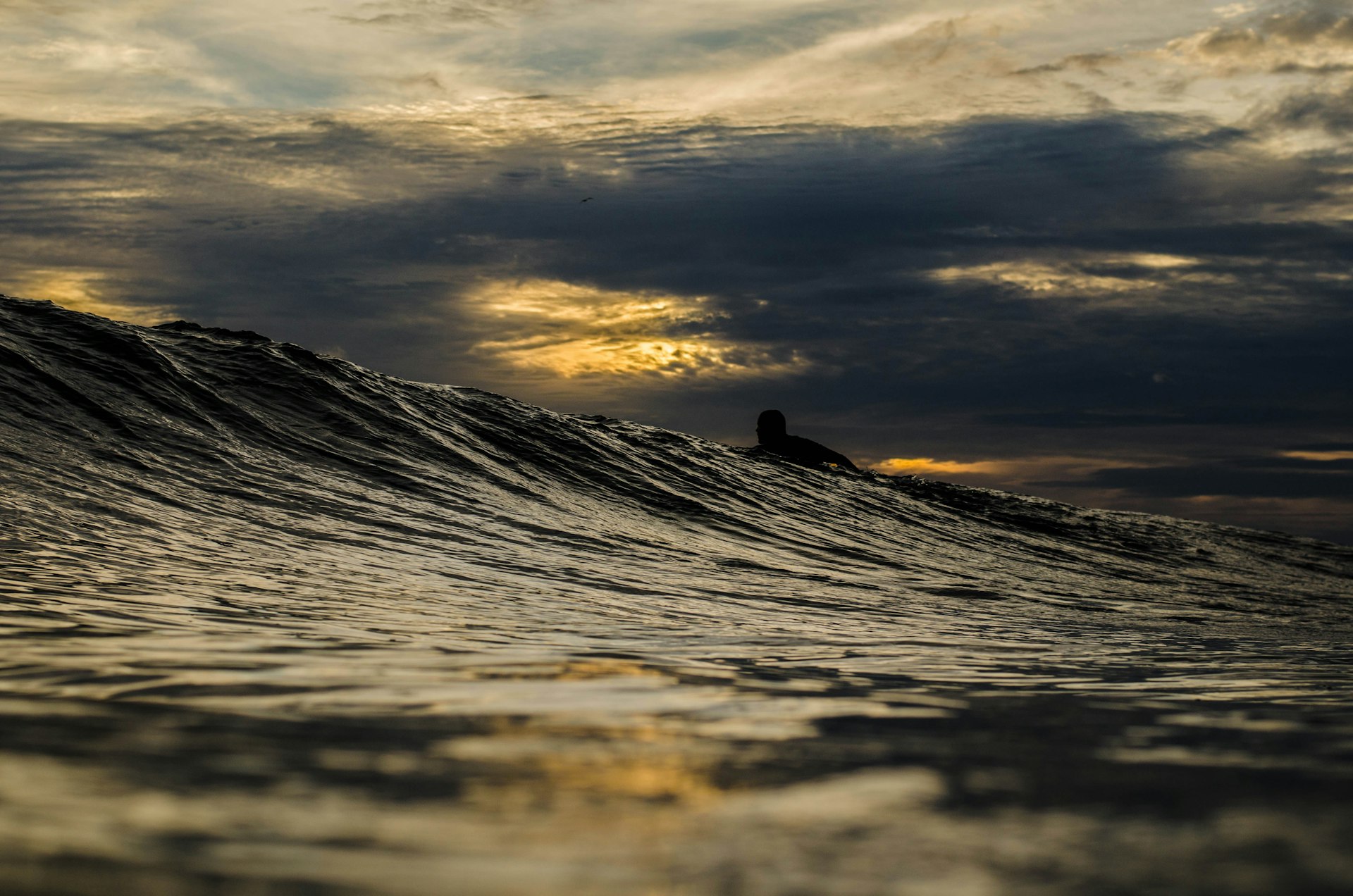 A surfer clears a large wave under dimly light skies; best beaches Nicaragua   