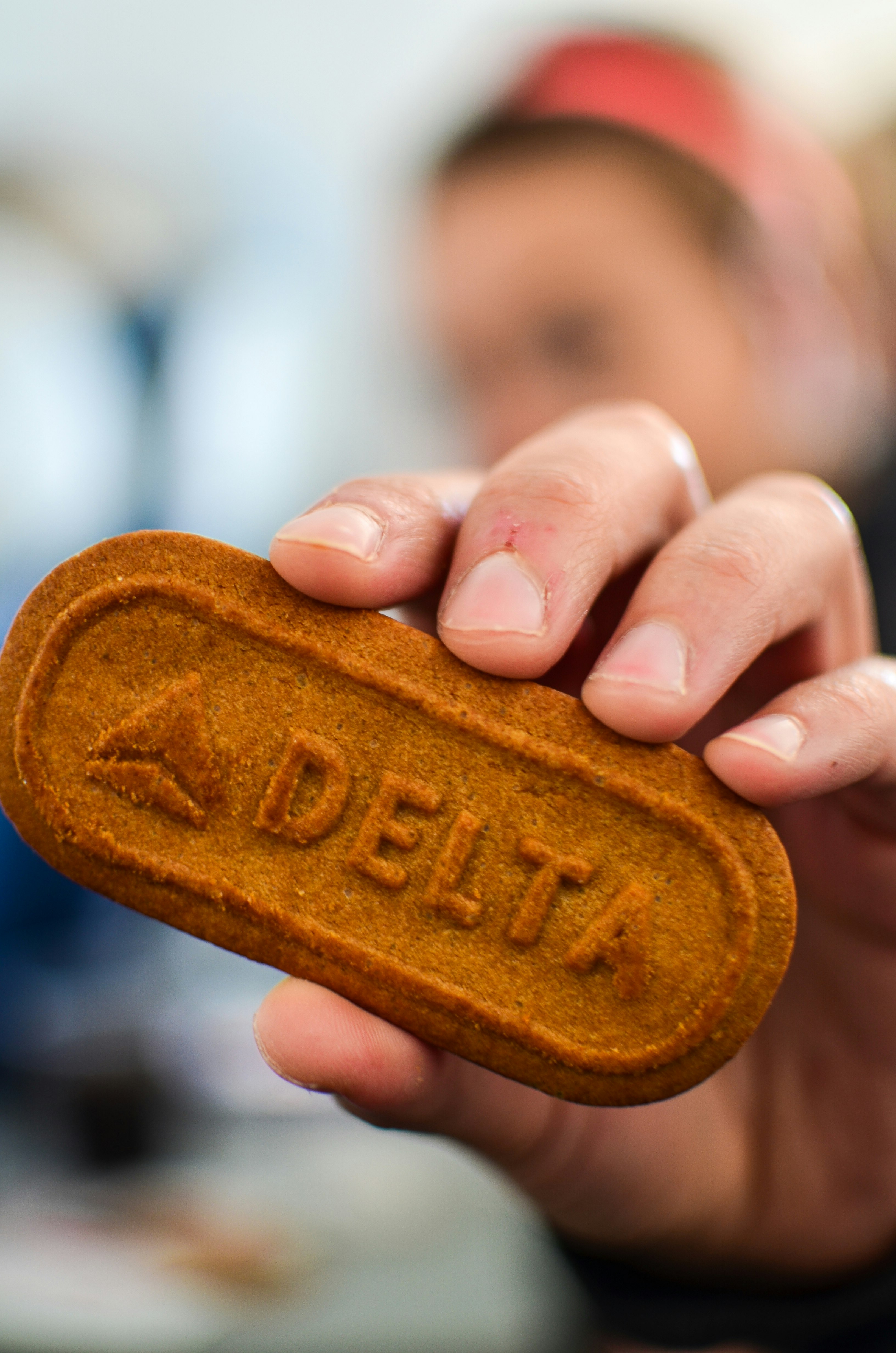 A person holds a cookie with the words "Delta" and the company's symbol etched on it.
