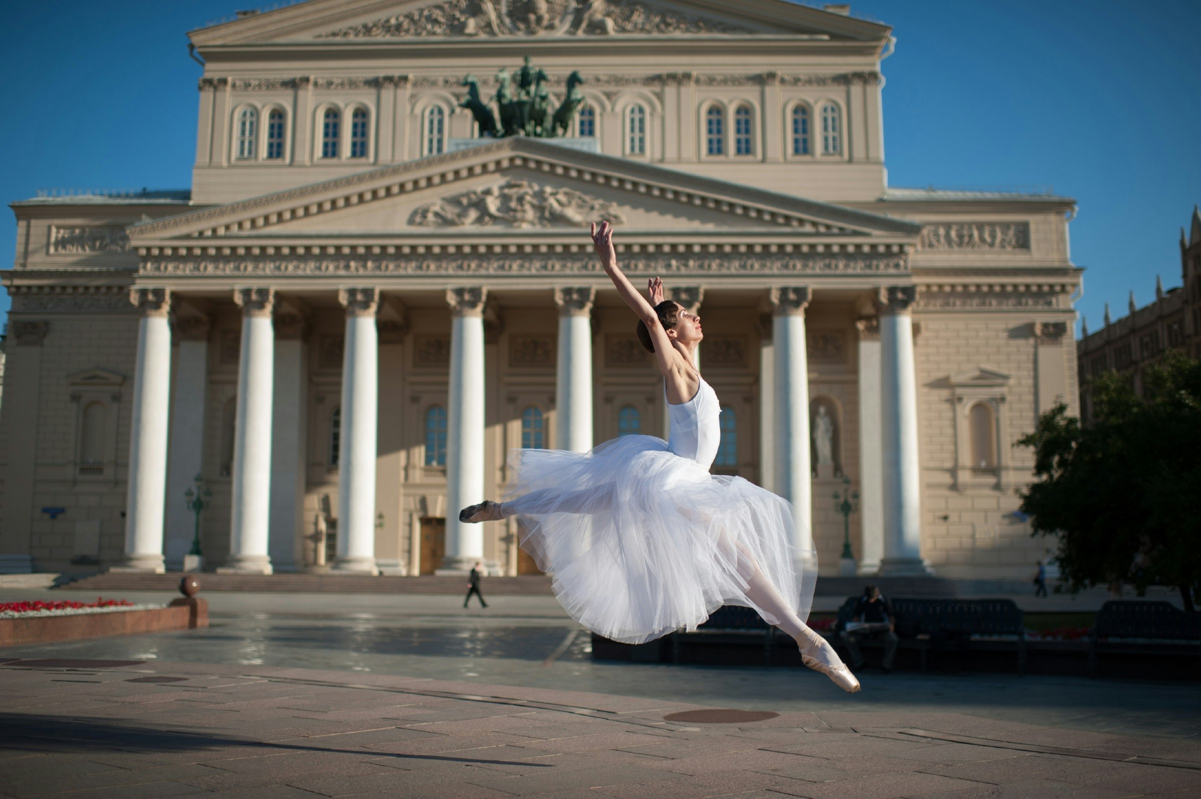 A professional ballerina leaping in front of the Bolshoi theatre in Moscow
