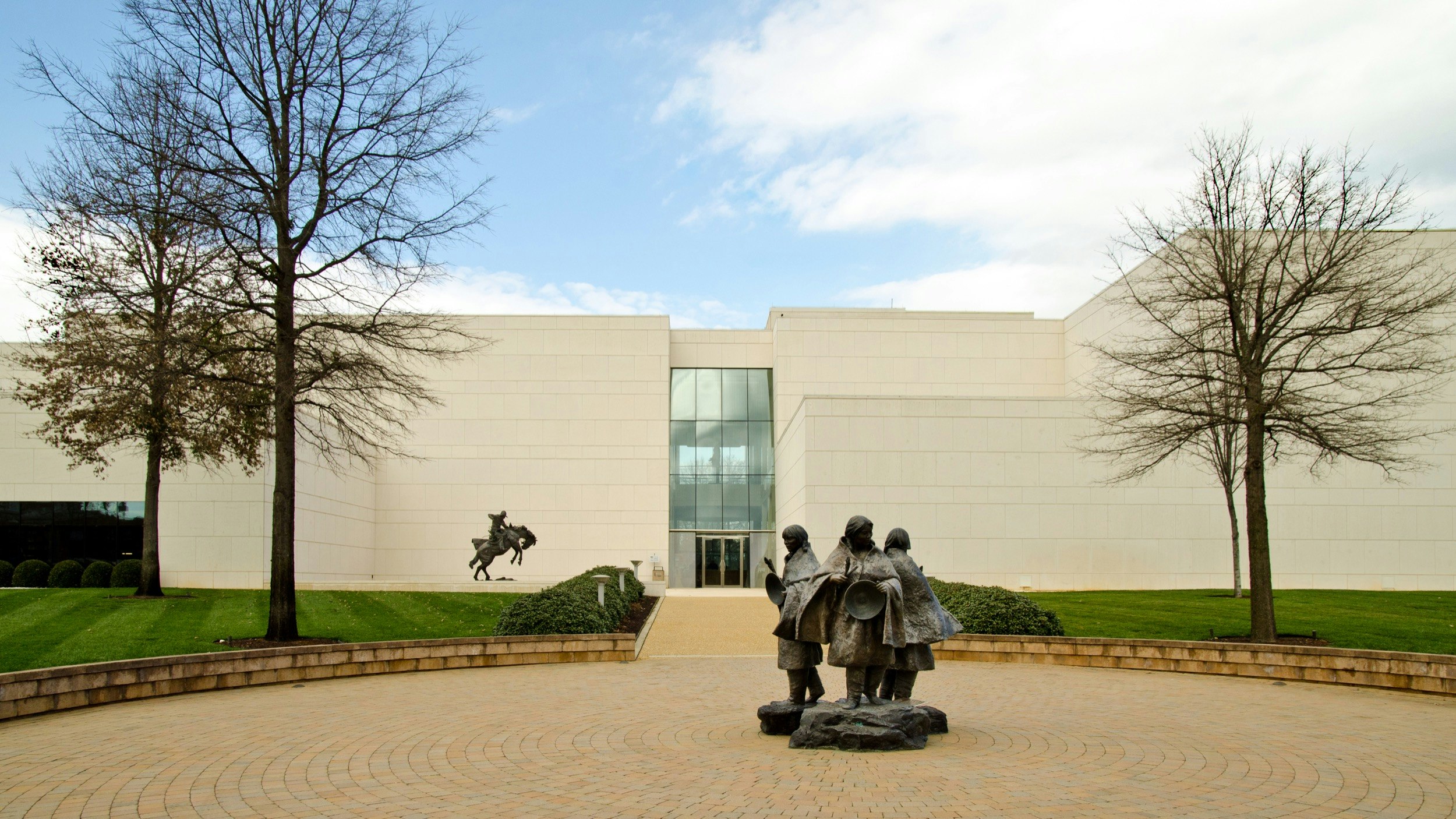 Statues of Native Americans and a bronco rider adorn the grounds of the Booth Western Art Museum