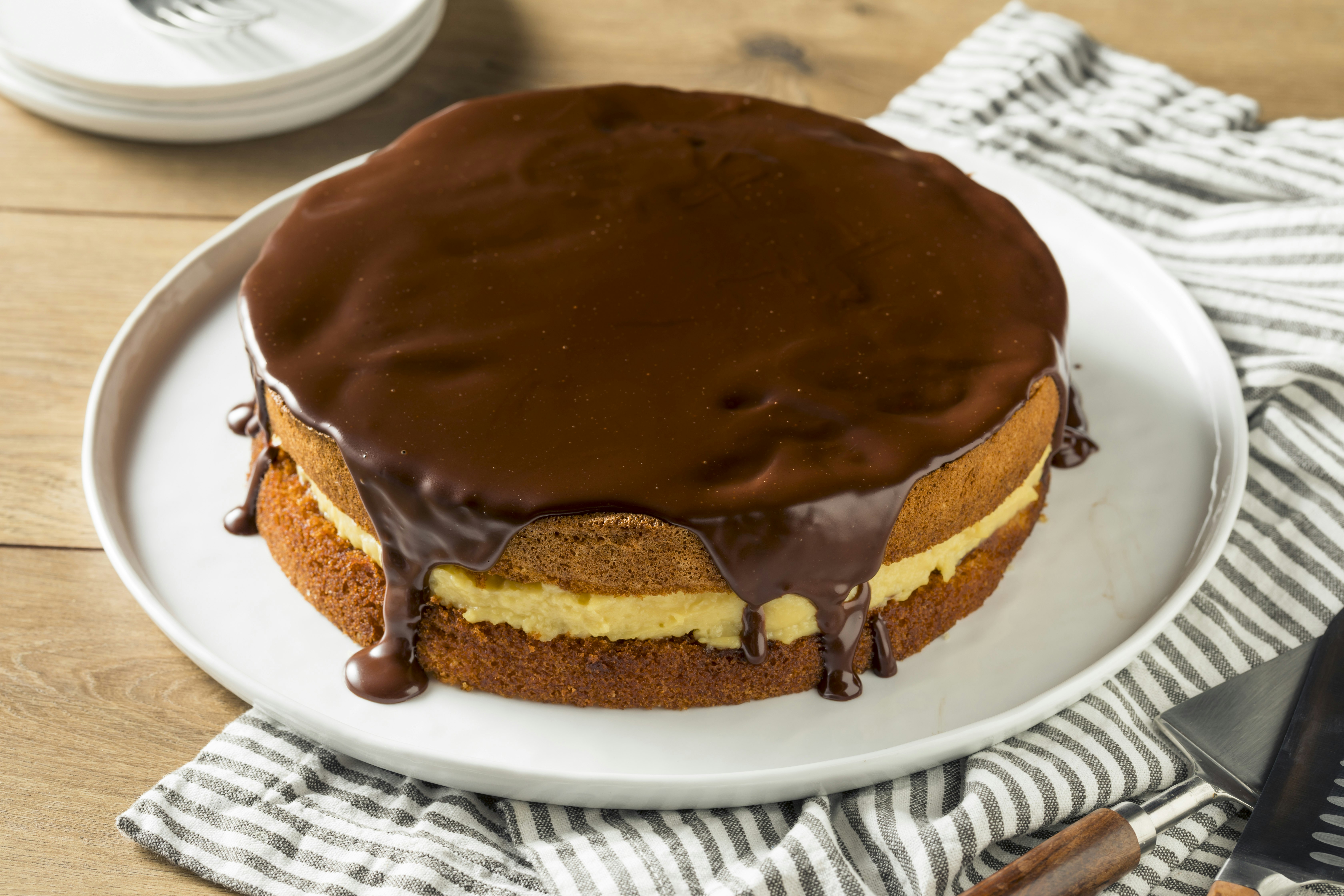 Chocolate ganache covers the top of a sponge cake that's filled with a light-colored cream